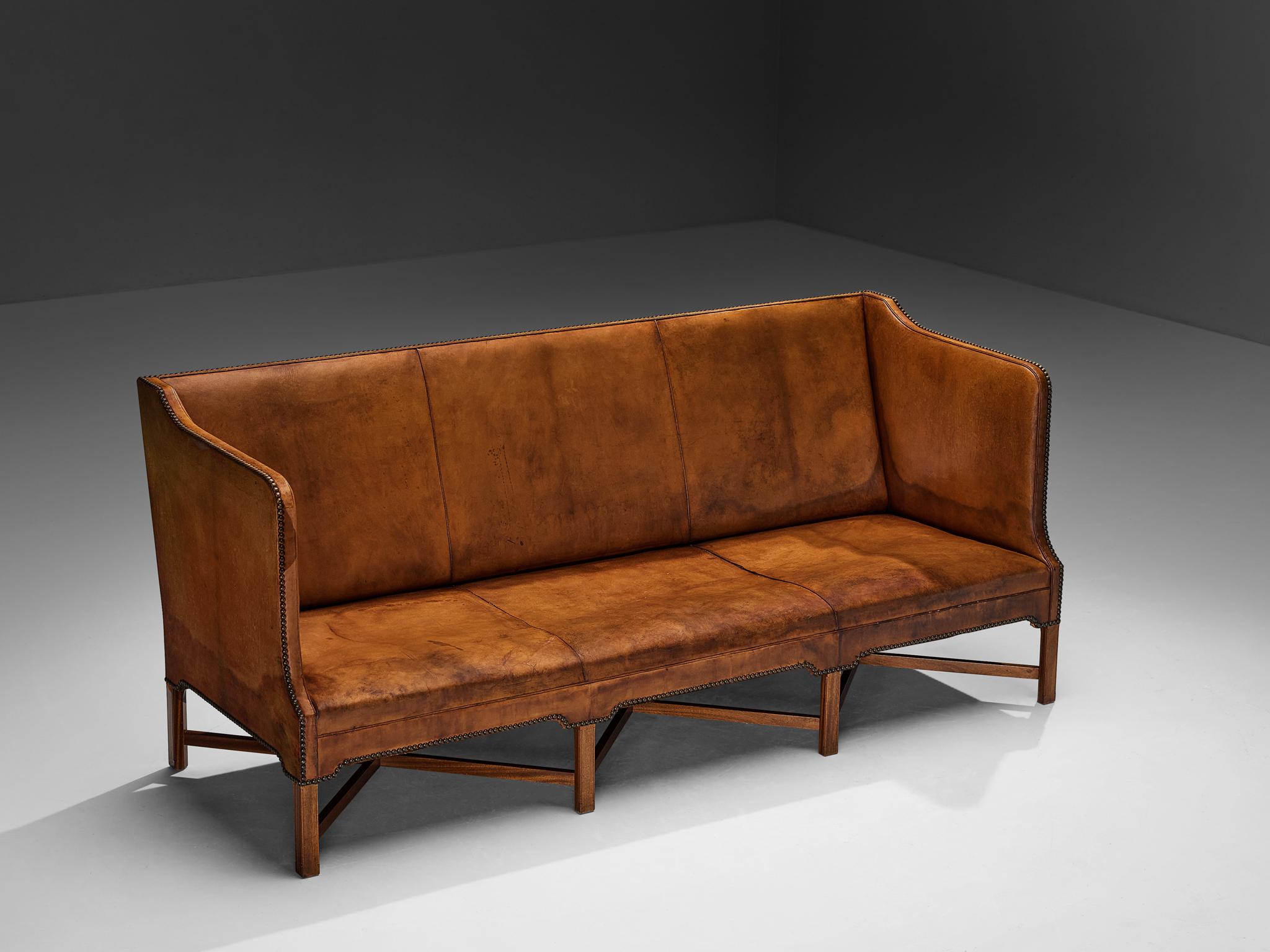 Kaare Klint for Rud. Rasmussen, sofa, model ‘4118’, Niger leather, mahogany, brass, Denmark, design 1930, production mid-1960s 

Kaare Klint originally designed the present three-seat sofa, known as 4118, for the office of the Prime Minister