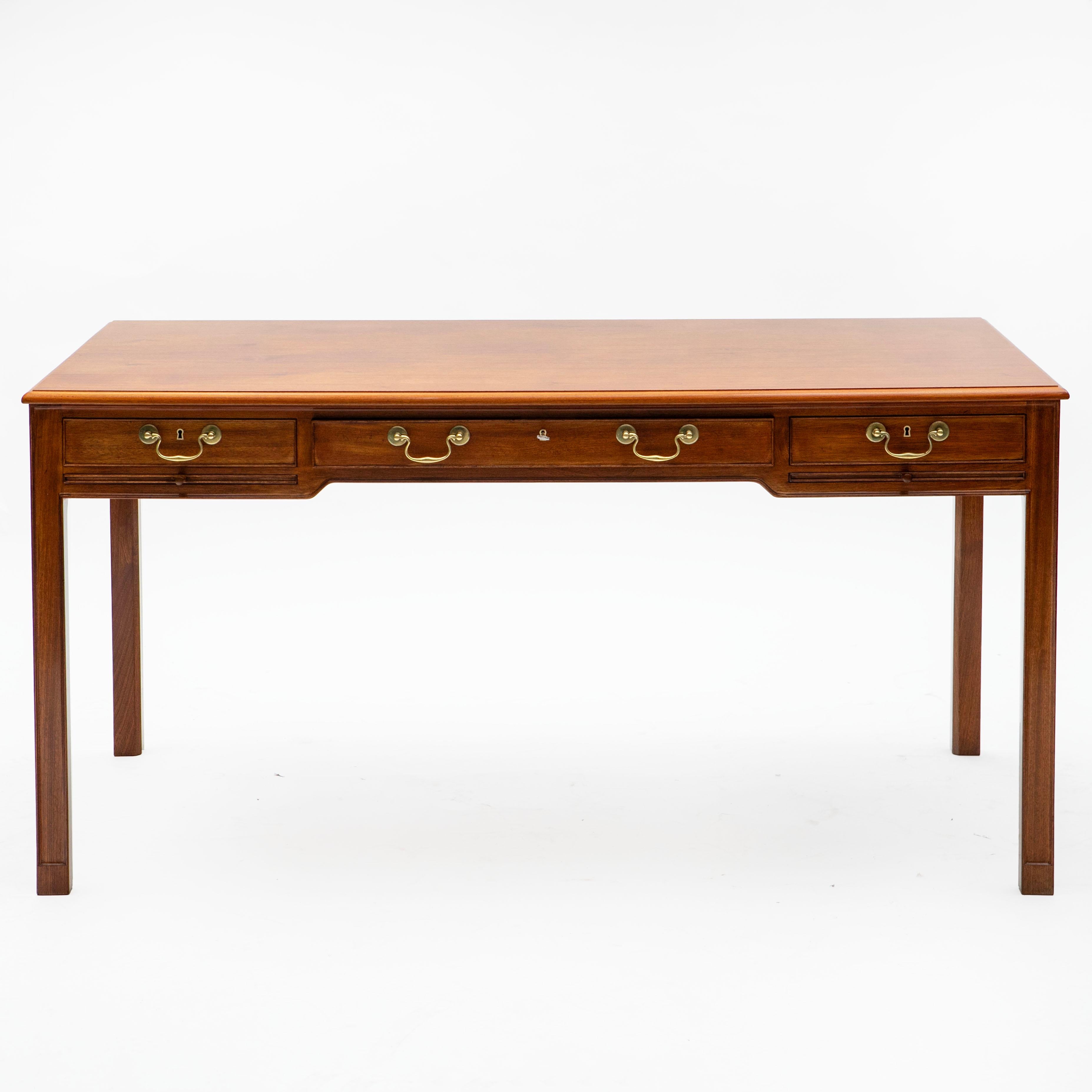 Writing desk by Kaare Klint, crafted in mahogany with a profiled edge on the tabletop and an apron with three drawers: a wide central drawer flanked by two smaller drawers, each equipped with a pull-out writing surface for added functionality. The