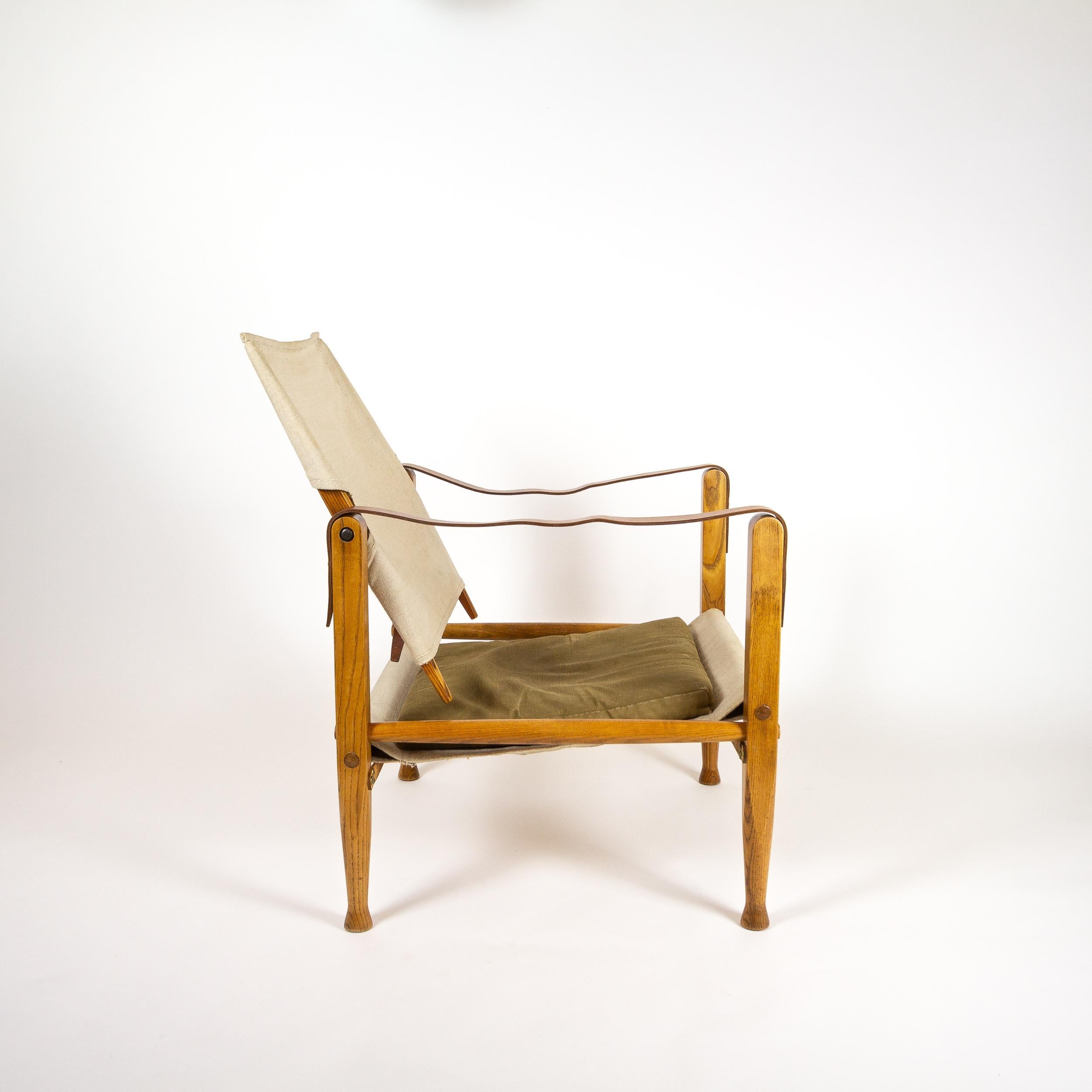 Ivory canvas Kaare Klint Safari chair with military green cushion and patinated cognac leather armrests and straps. Designed by Klint in 1933, produced by Rud. Rasmussen for Illums Bolighus, Copenhagen, Denmark, 1960s. Completely original with