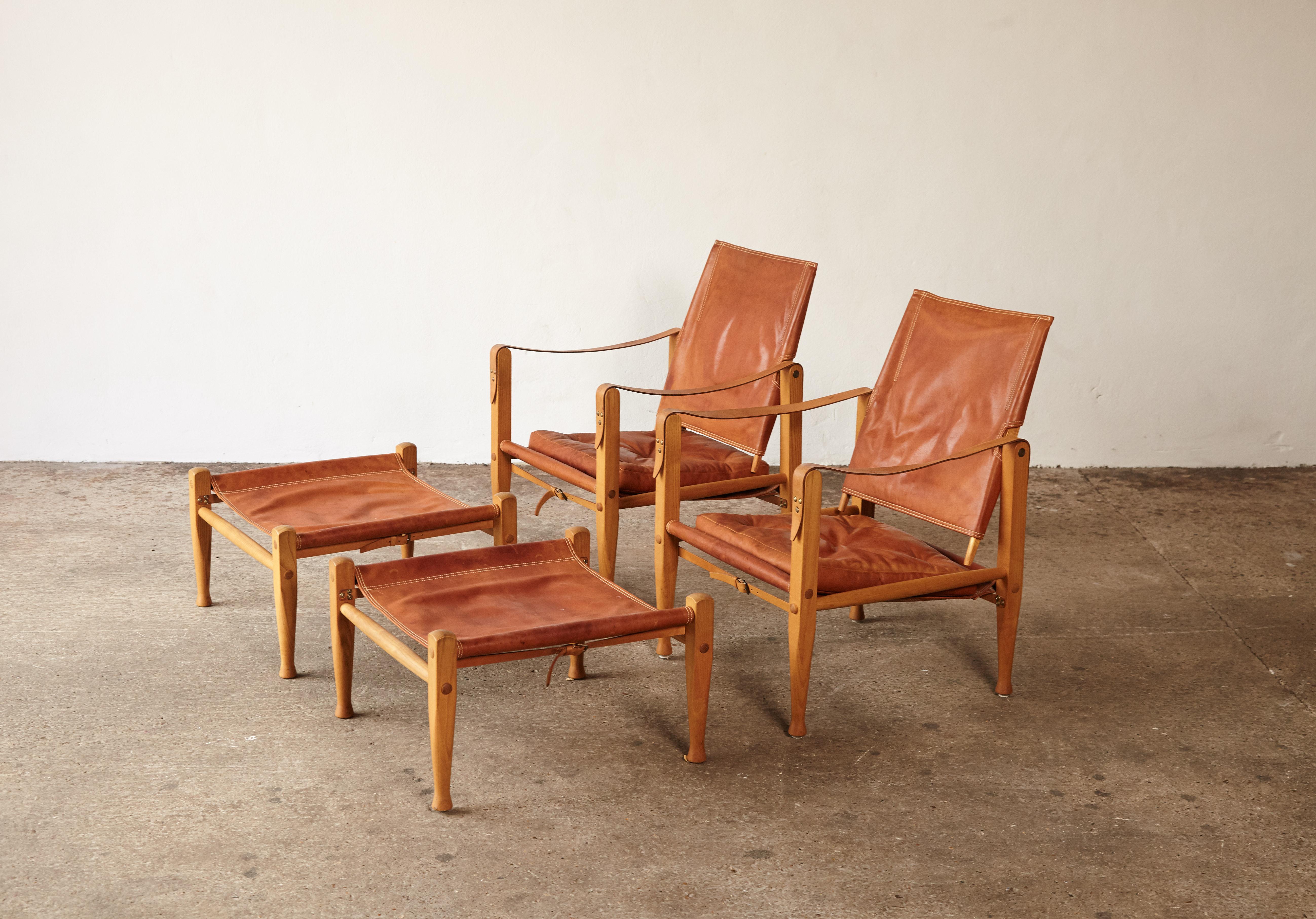 A wonderful and rare pair of Kaare Klint Safari Chairs and Ottomans, produced by Rud Rasmussen, Denmark, 1960s. Ash frames and tan/cognac leather seats. Makers label intact. Good vintage condition with some marks, stains and age related signs of use