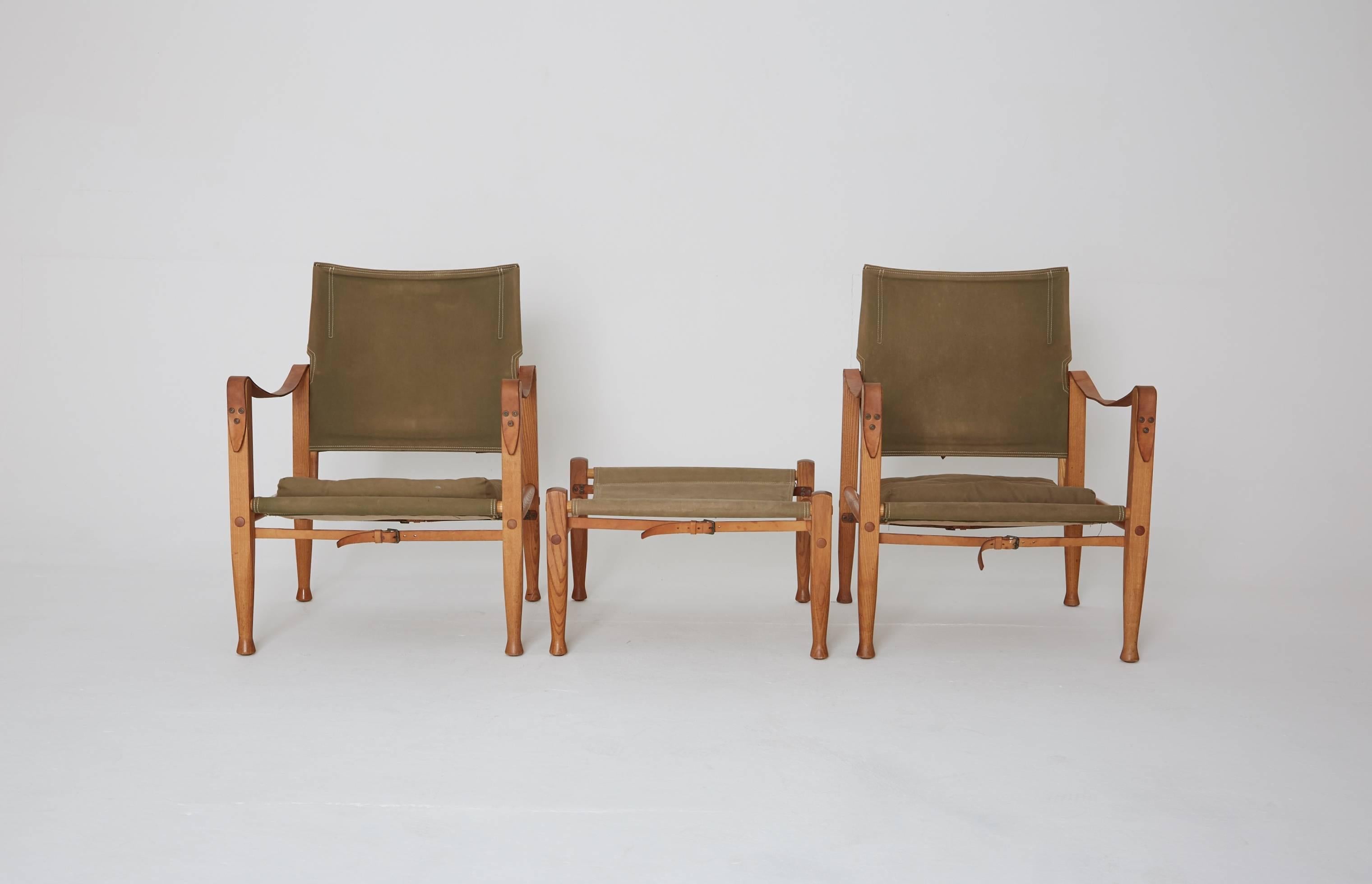 A pair of Kaare Klint safari chairs with rare ottoman, made by Rud Rasmussen, Denmark, 1960s. Olive / khaki canvas and ashwood.   Ships worldwide.
