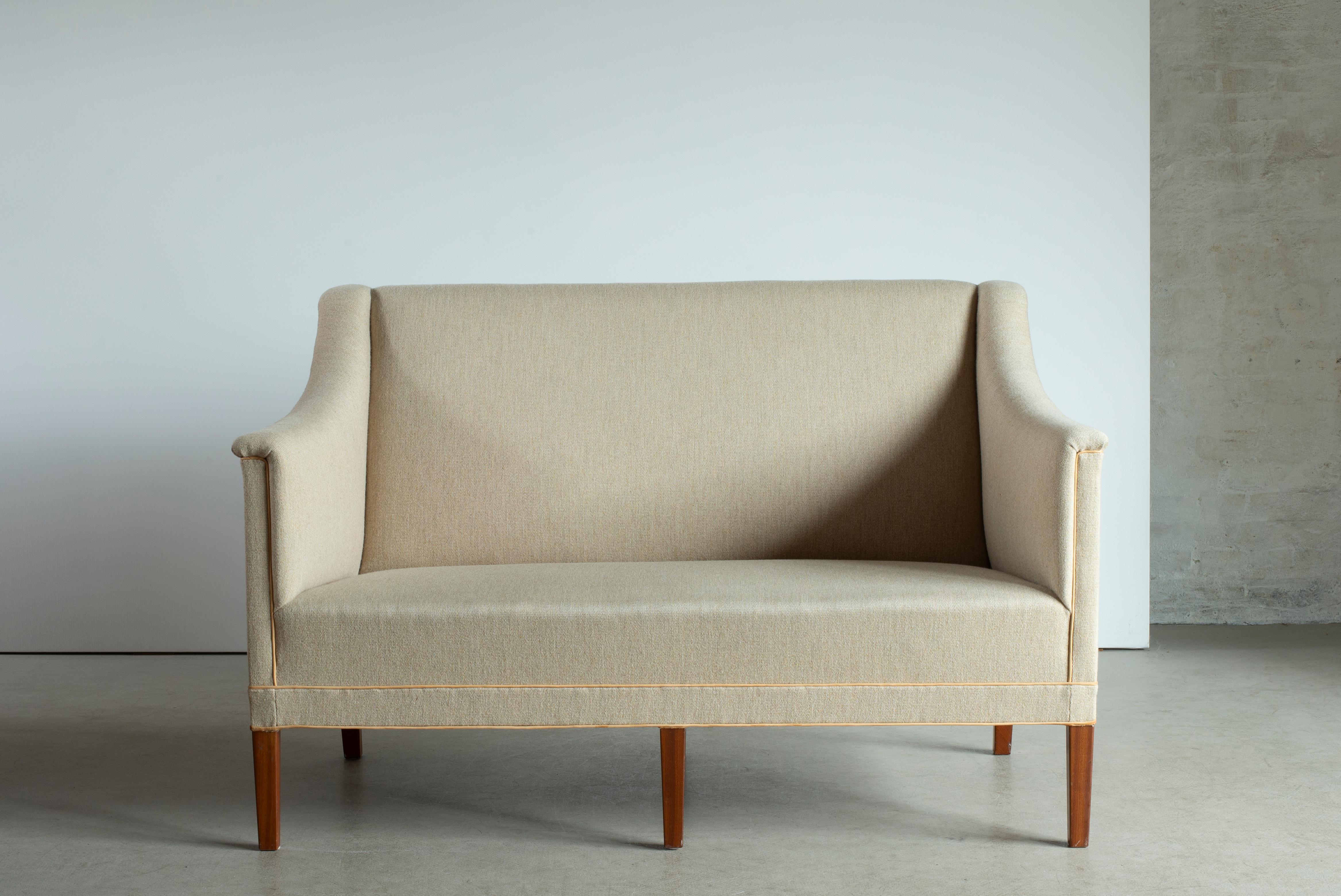 Kaare Klint 2 Personen Sofa mit Beinen aus Mahagoni. Sitz, Seiten und Rücken mit hellem Stoff gepolstert. Ausgeführt von Rud. Rasmussen.