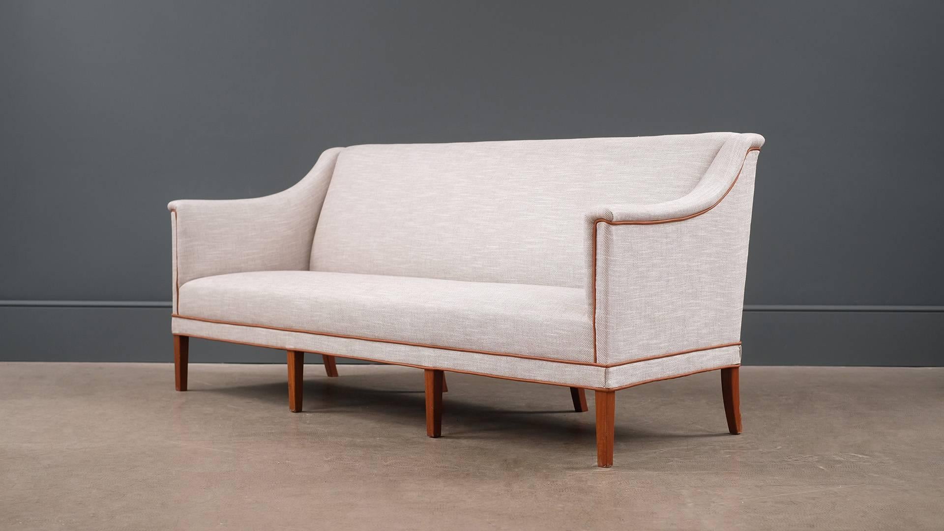 Monumental sofa designed by Kaare Klint for Rud. Rasmussens Snedkerier, Denmark 1941. Ultra elegant and super high quality piece with eight solid teak legs. Fully reconditioned and reupholstered in beautiful fabric by Romo with tan leather piping.