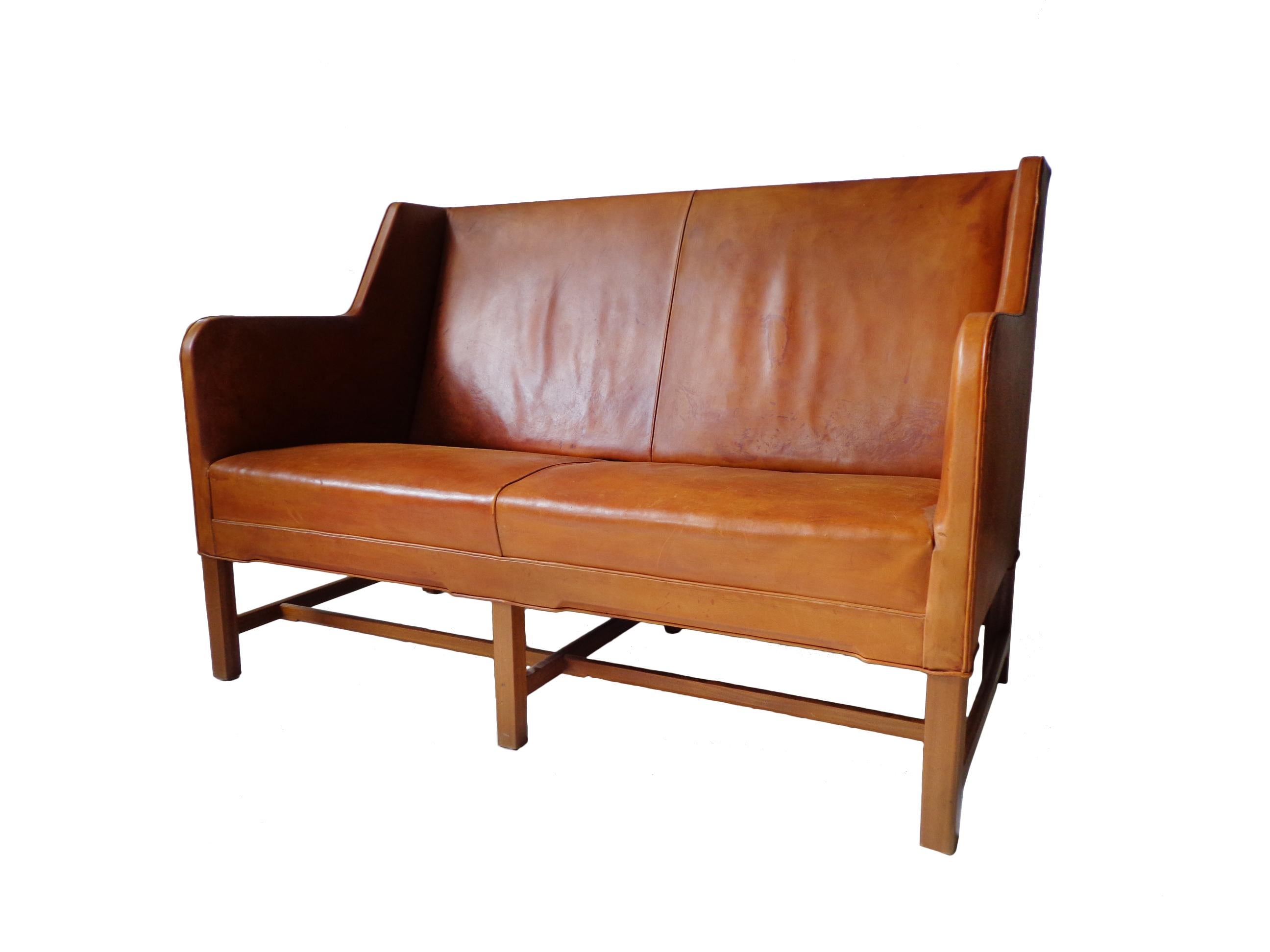 Two-seater sofa model 5011 in original cognac leather and six-legged mahogany base. Produced by Rud. Rasmussen Cabinetmakers, Denmark. Minor marks on the frame, patina to the leather. Back covered in original canvas.
Shown at the Copenhagen