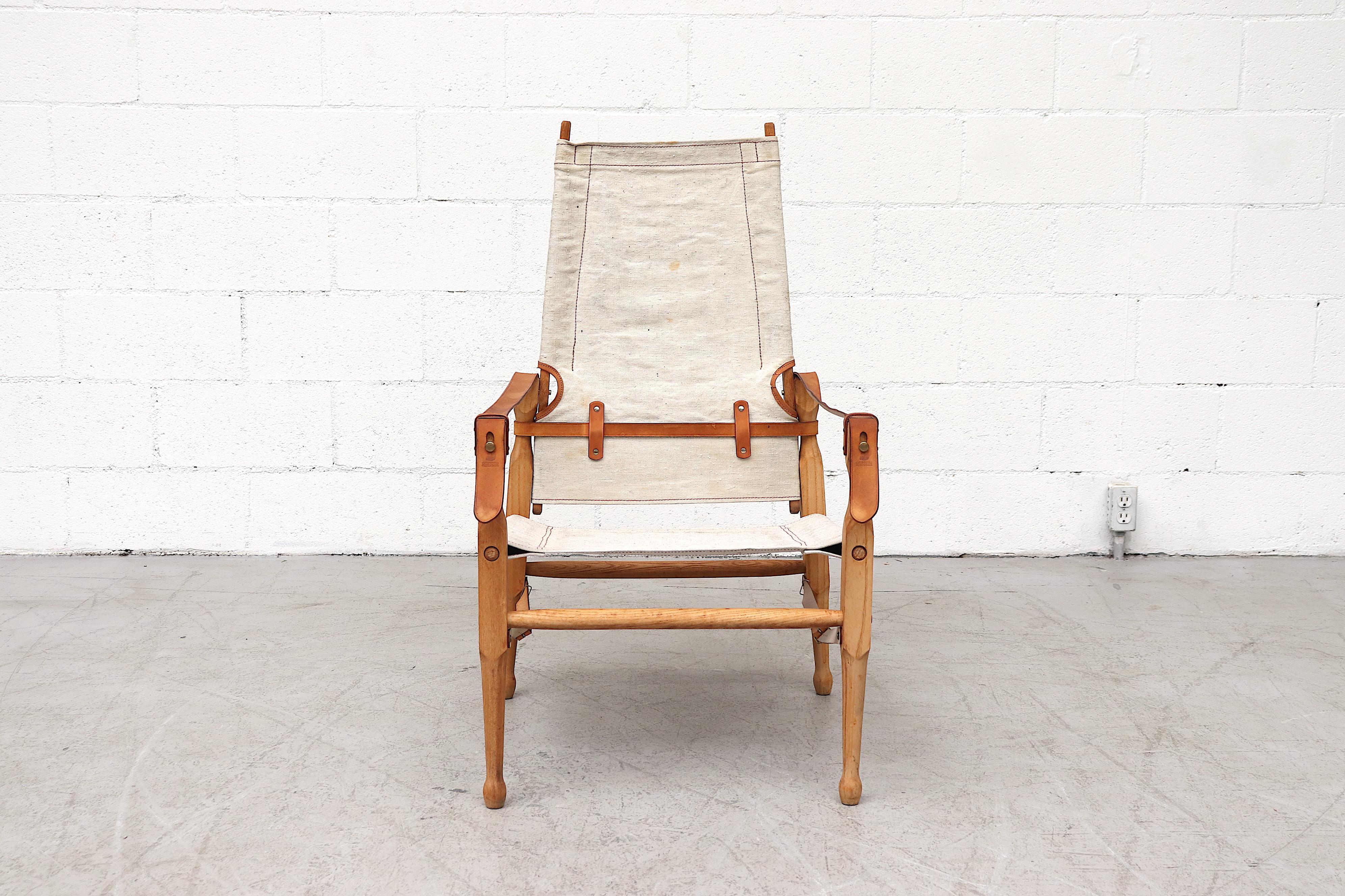 Attractive Kaare Klint style wood and canvas safari chair with leather strap arm rests and accents. In original condition with delicate elegance and effortless style. Visible wear to frame, canvas and leather. Wear is consistent with its age and use.