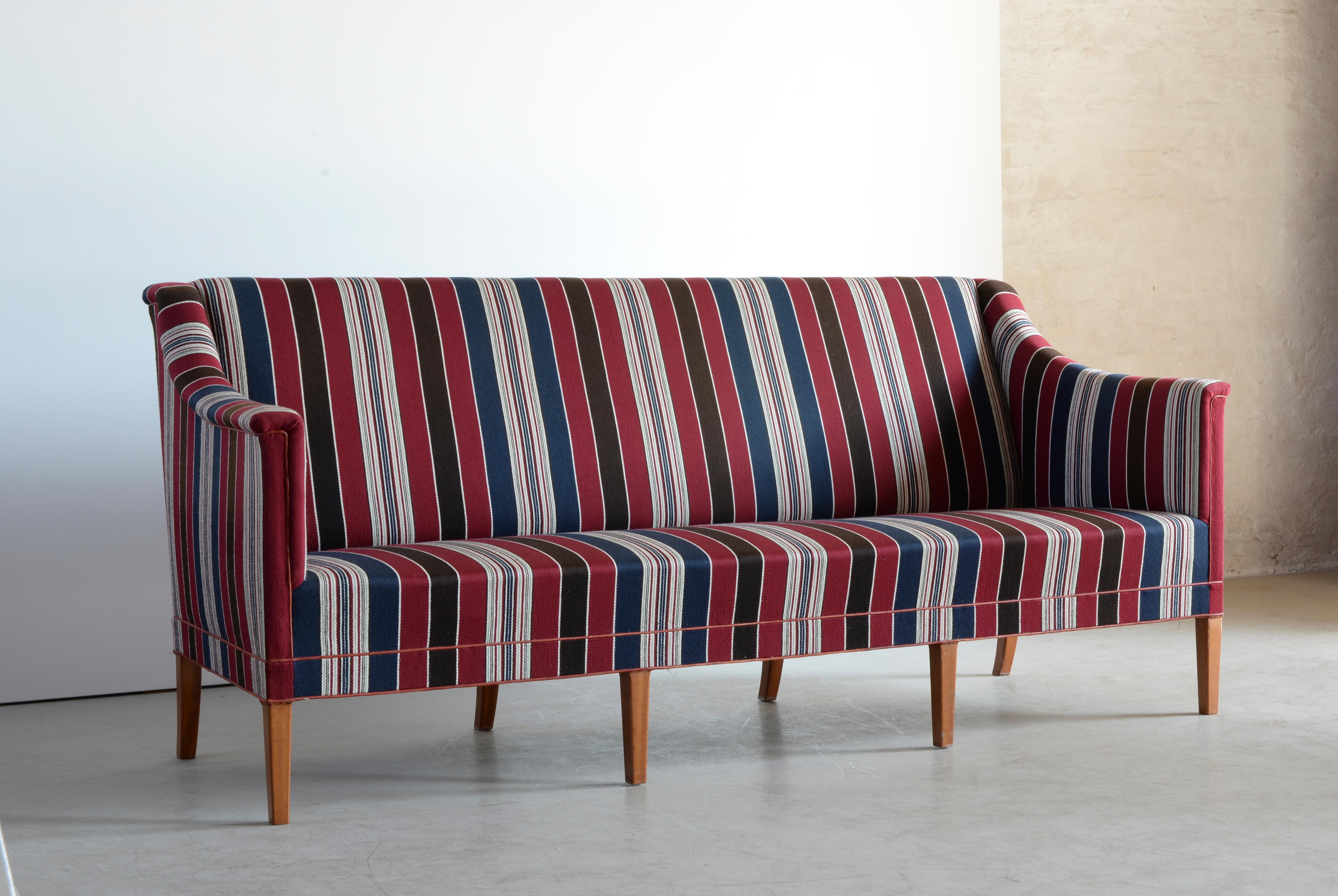 Kaare Klint. A three-seat sofa with mahogany legs, seat, sides and back with blue-, red- and whitestriped Greek Savak. Executed by Rud. Rasmussen, Copenhagen.
