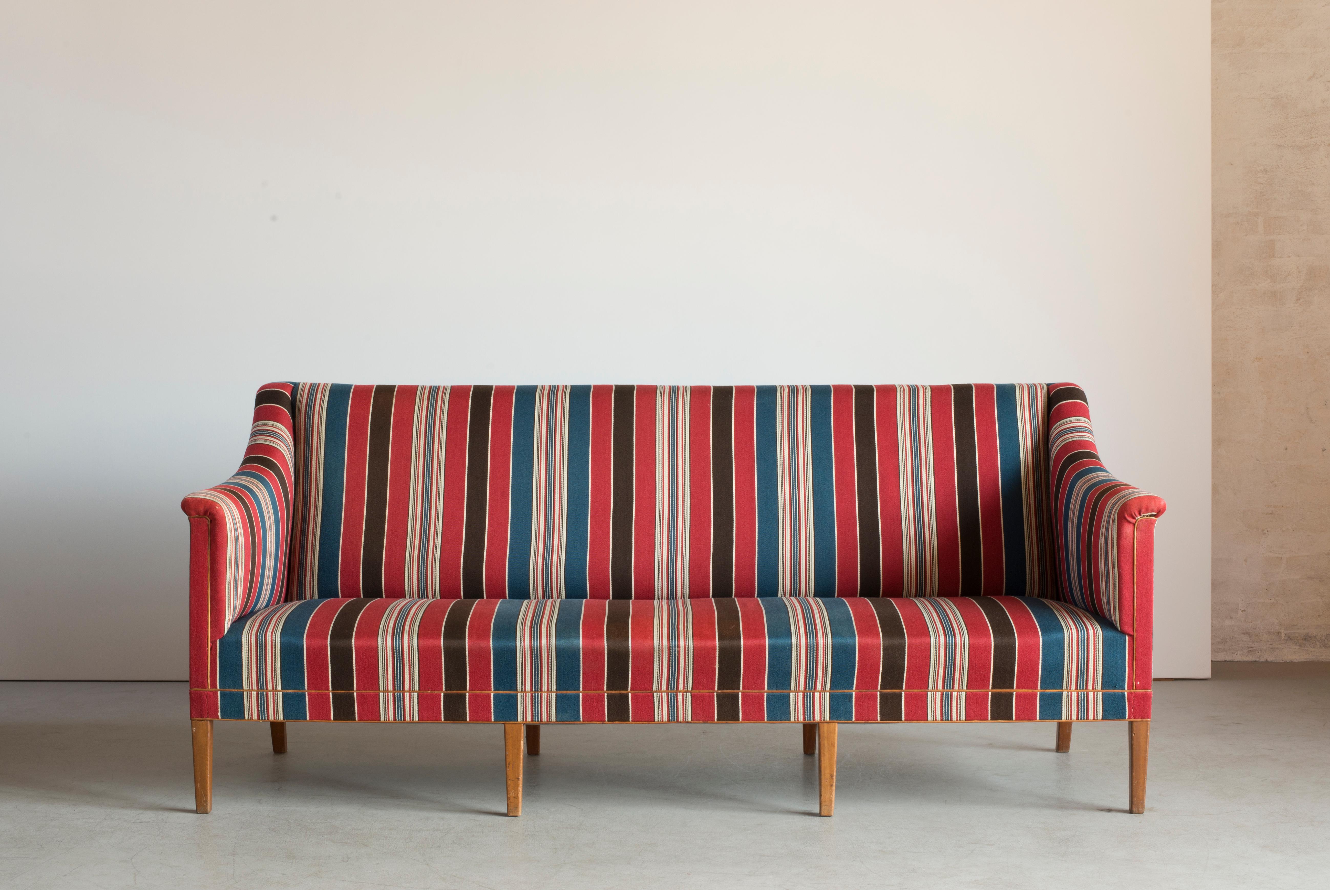 Kaare Klint three seat sofa with eight legs of Mahogany. Seat, sides and back upholstered with blue, red and white striped 