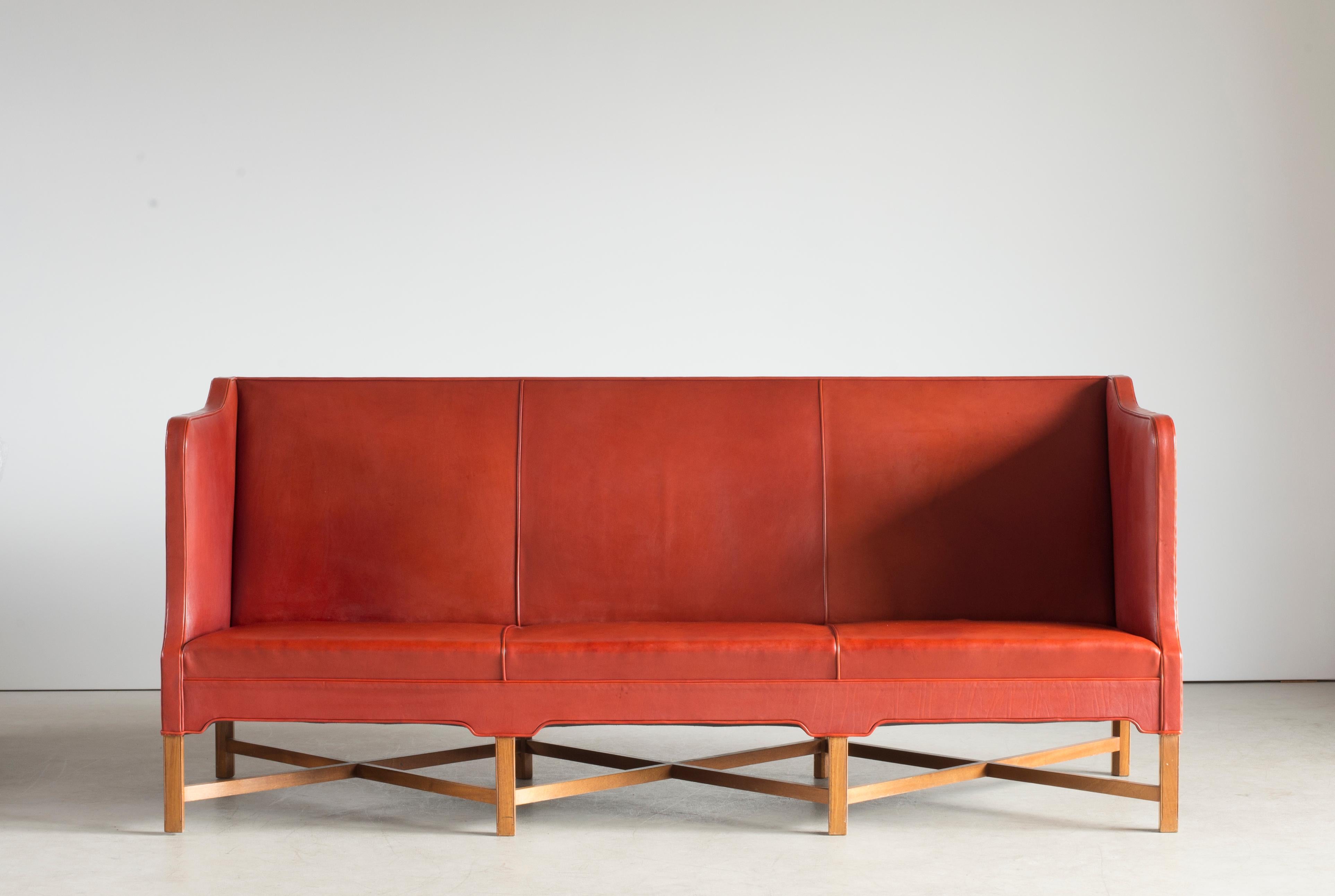 Kaare Klint freestanding three-seat sofa on eight-legged, profiled mahogany cross-frame. Sides, seat and back upholstered with patinated red leather. Model 4118. Executed by Rud. Rasmussen, Nørrebrogade, Copenhagen.
