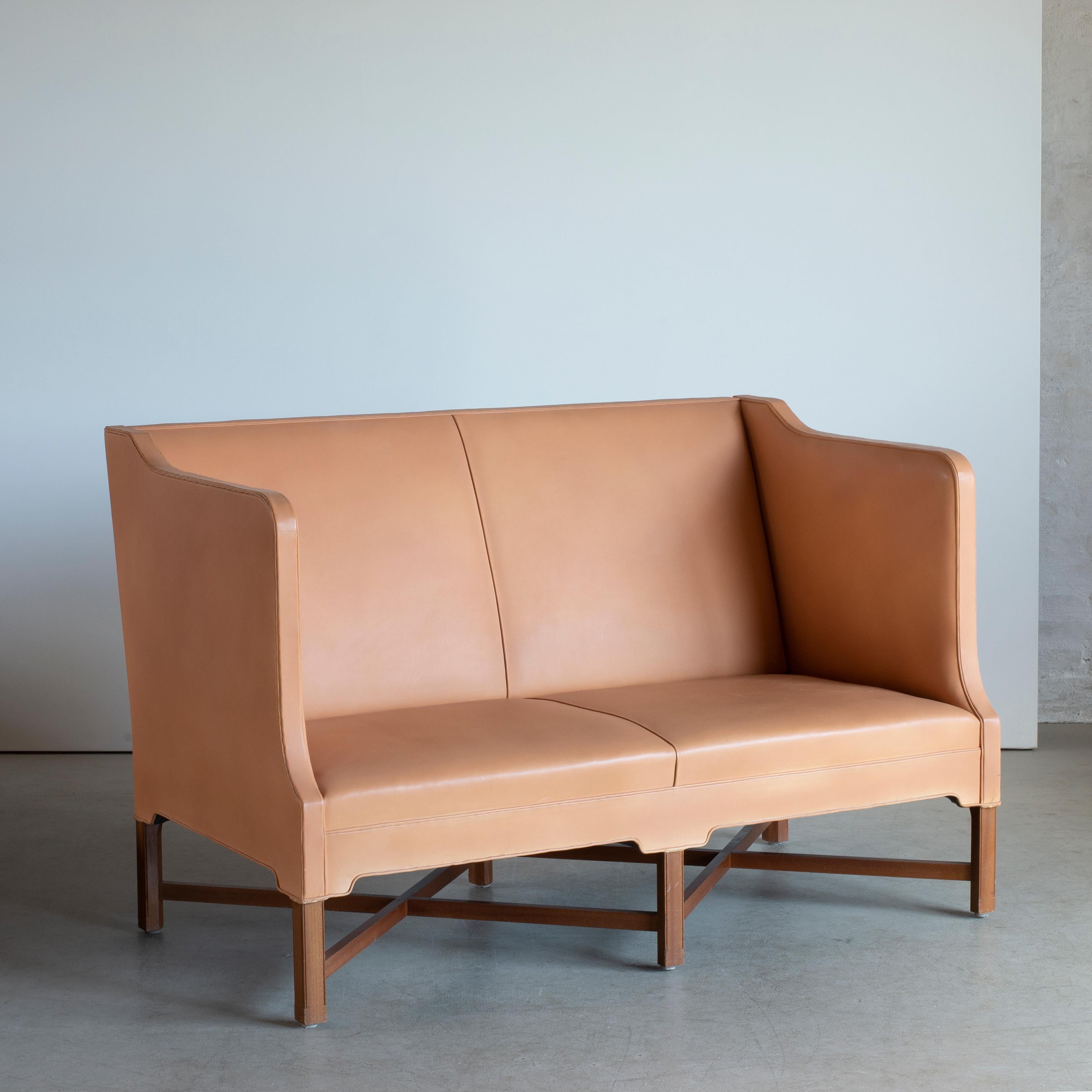 Kaare Klint freestanding two-seat sofa on six-legged, profiled mahogany cross-frame. Sides, seat and back upholstered with leather. Executed by Rud. Rasmussen, Copenhagen.