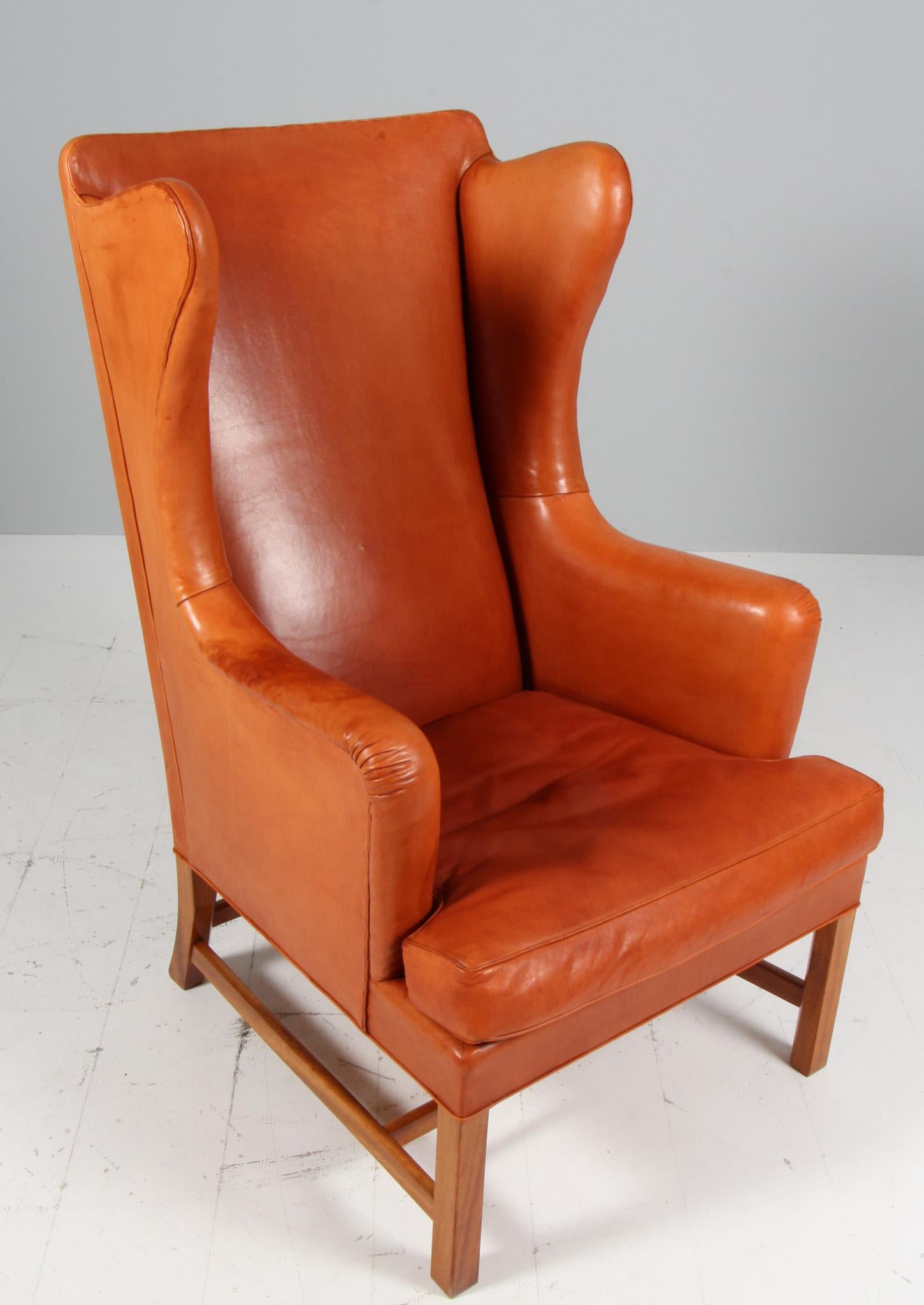   Beautiful Classic wingback chair and footstool designed by Kaare Klint and made by master cabinet maker Rud Rasmussen, Denmark. Original upholstered with Niger skin with beautiful patina.
Legs of mahogany.

Model 6212, made by Rud Rasmussen
