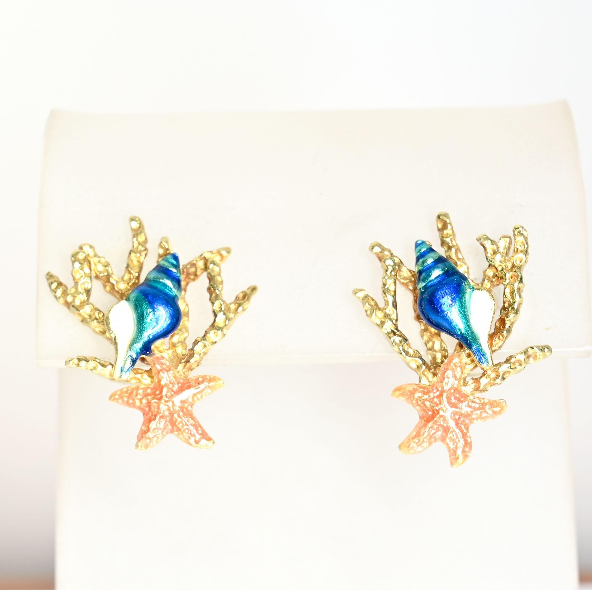 Boucles d'oreilles en émail de belle facture, chacune représentant un coquillage, une étoile de mer et un corail. Ils sont fabriqués par Kabana au Nouveau-Mexique. Le métal est de l'or 18 carats. Convient pour les dos de poteau. Les boucles