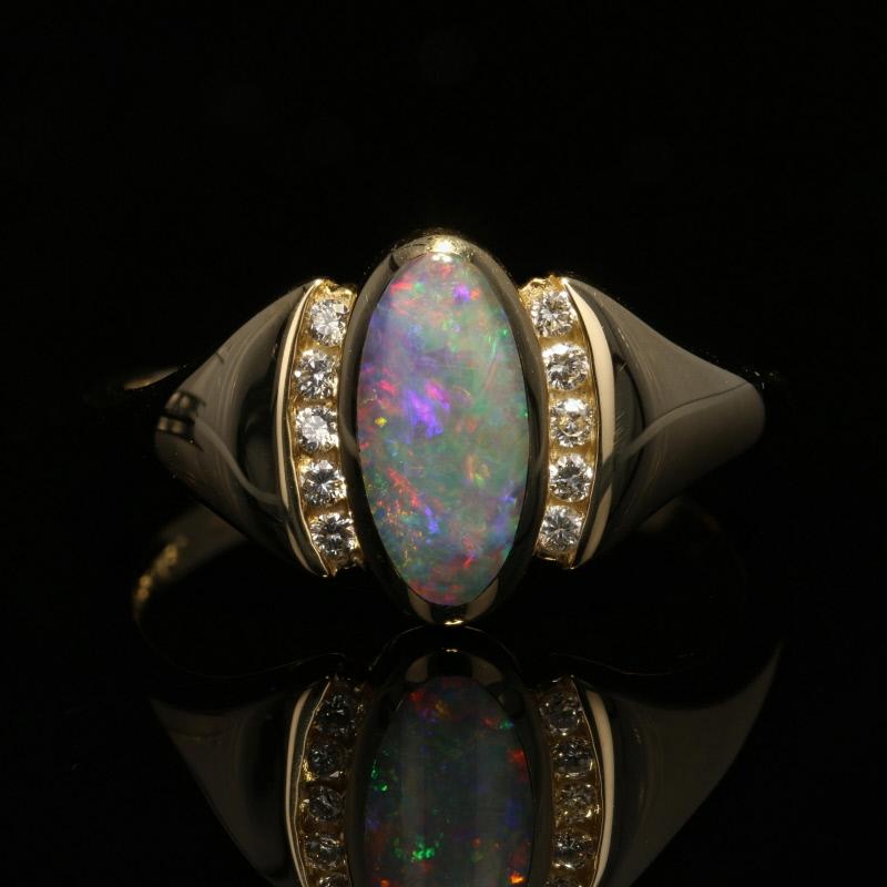 Simply exquisite, this NEW Kabana ring makes a wonderful gift for someone celebrating a special birthday or milestone anniversary! The ring is fashioned in 14k yellow gold and features an opal cabochon with stunning neon-green, cobalt-blue, and