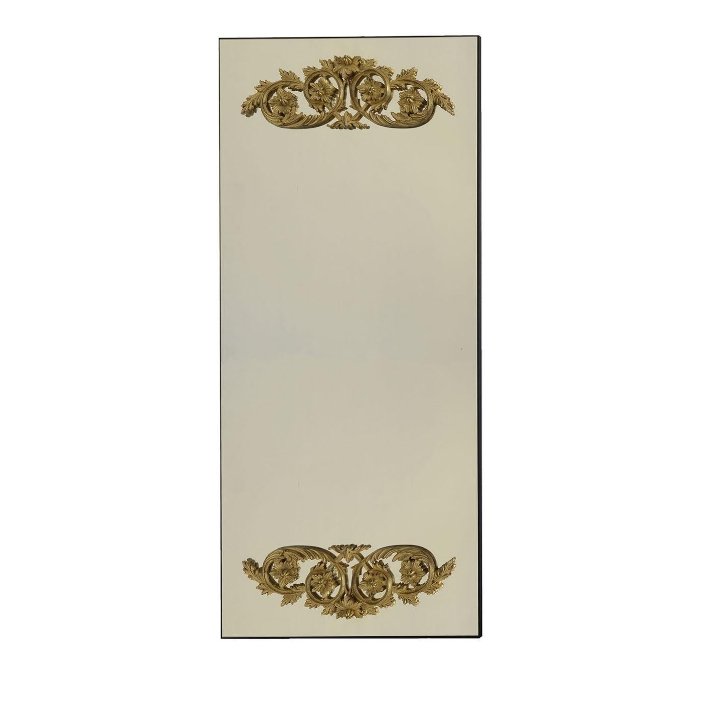 Superba sintesi di influenze barocche e minimaliste, questo specchio da parete rettangolare sfoggia seducenti contrasti e minuziosi dettagli manuali. Le ghirlande floreali in legno di tiglio, rifinite in foglia d'oro anticato, che adornano la