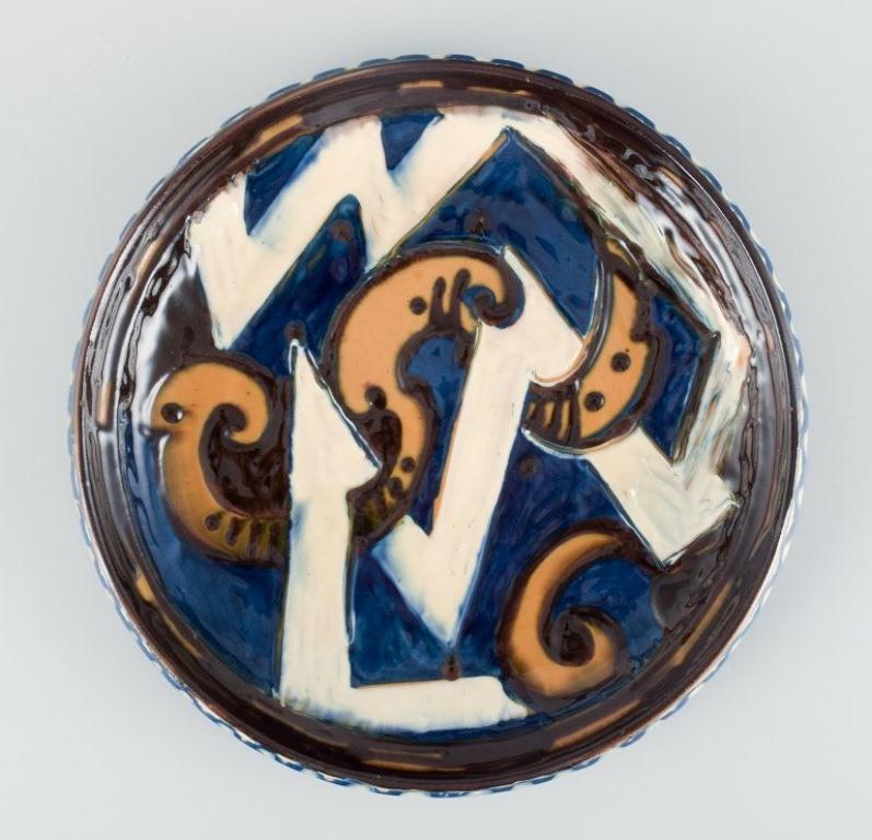 Kähler ceramic dish in cow horn technique. 
Abstract motif with glaze in blue, yellow, and white tones. 
Approximately from the 1930s.
In excellent condition with a few minor chips. See photo.
Marked.
Dimensions: Diameter 28.5 cm x Height 4.0 cm.