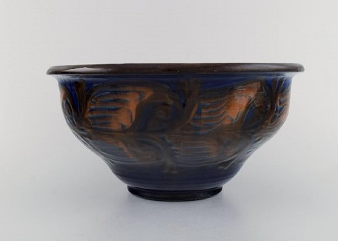 Kähler, Denmark. Bowl in glazed stoneware. Orange foliage on blue background, 1930s-1940s.
Measures: 26.5 x 13 cm.
Signed.
In excellent condition.
 