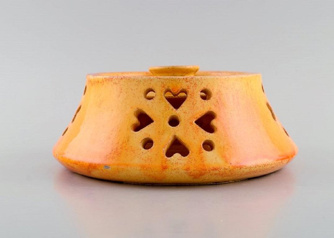 Kähler, Denmark. Candlestick with heater in glazed stoneware. 
Beautiful orange uranium glaze. Mid-20th century.
Heater measures: 20 x 8 cm.
The candlestick measures: 10.5 x 7 cm.
In excellent condition.
Signed.