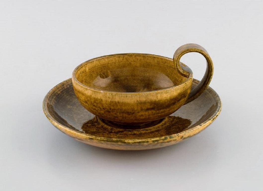 Kähler, Denmark. Egoist tea set in glazed stoneware. 
Beautiful yellow uranium glaze. 
Mid-20th century.
Consisting of a teacup with a saucer and plate.
The cup measures: 13 x 7 cm (incl. Handle).
Saucer diameter: 16.5 cm.
Plate diameter: 19