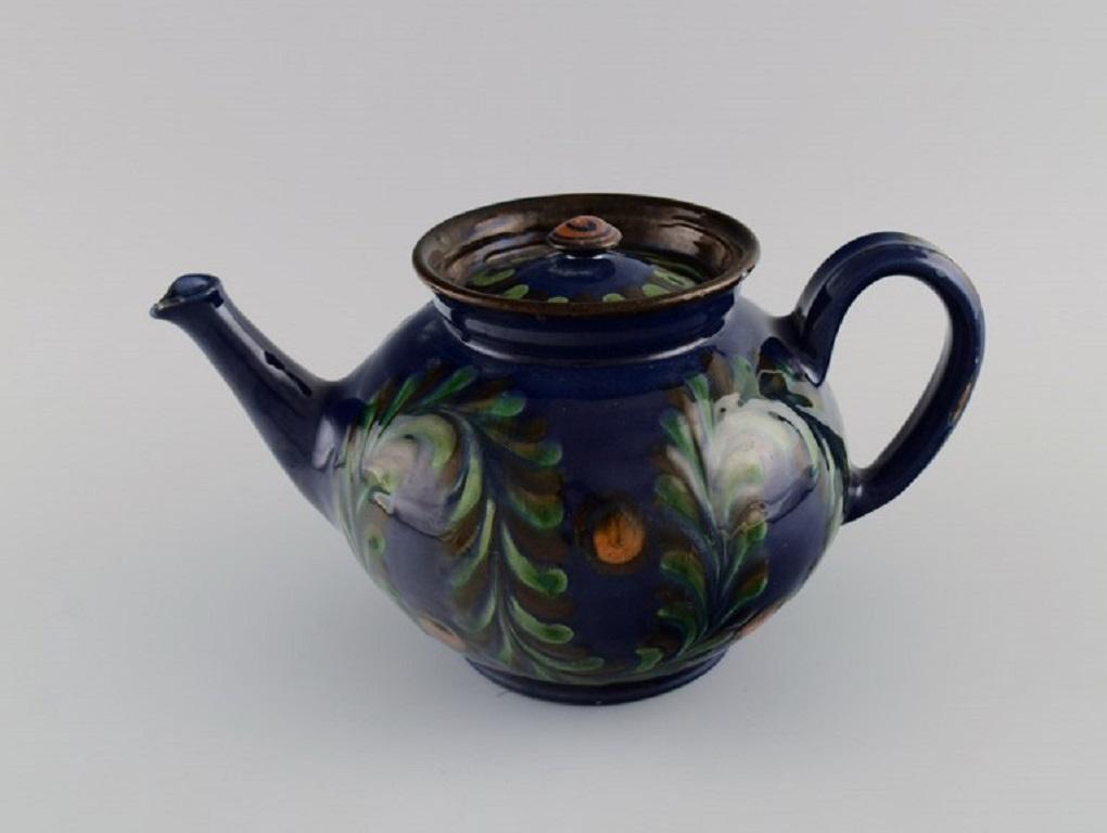 Kähler, HAK. Large teapot in glazed ceramics. Flowers and foliage on a dark blue background. 
1930s / 40s.
Measures: 26.5 x 14 cm.
Signed: HAK.
In good condition. A few small chips on the spout and minor wear.