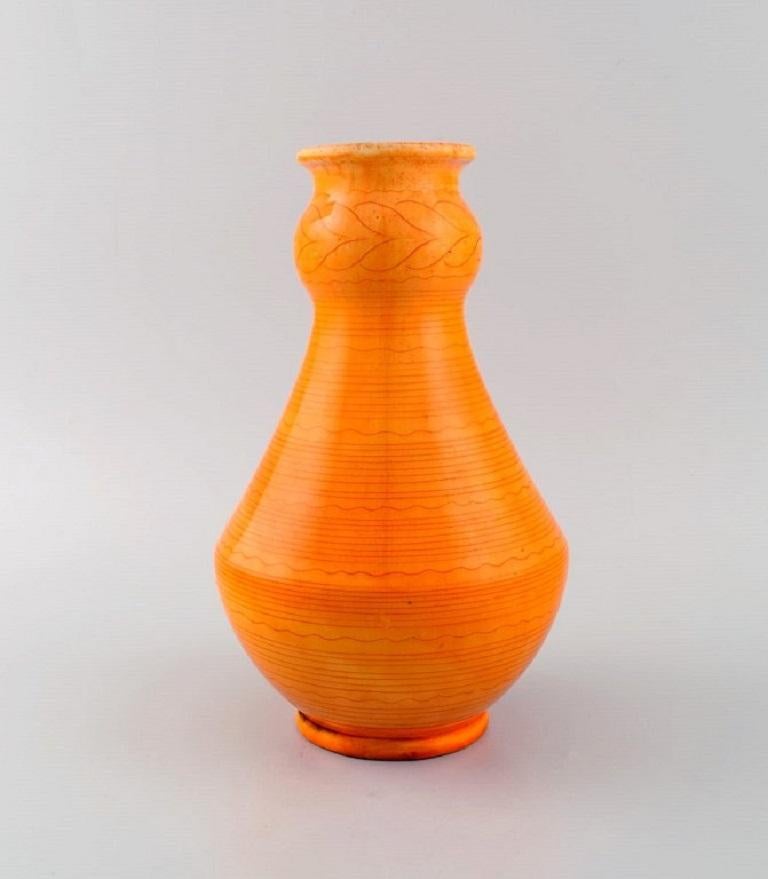 Kähler, Denmark. Vase in glazed stoneware. 
Beautiful orange uranium glaze with horizontal wavy stripes. 1930s / 40s.
Measures: 23 x 14.5 cm.
Signed.
In excellent condition.