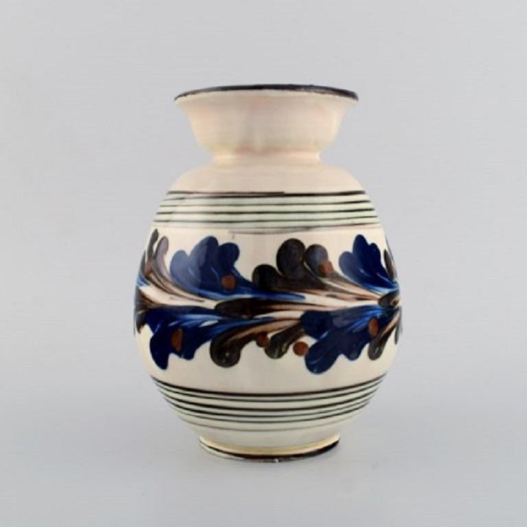 Kähler, HAK. Glazed stoneware vase in modern design, 1930s-1940s. 
Blue flowers on a cream background.
Measures: 24 x 8.5 cm.
Stamped.
In very good condition.