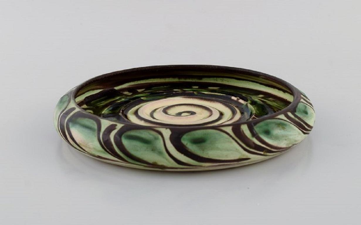Kähler, HAK. Round bowl in glazed stoneware. Green leaves on a cream-colored background. 
1940s.
Measures: 19.5 x 3 cm.
In excellent condition.
Signed.