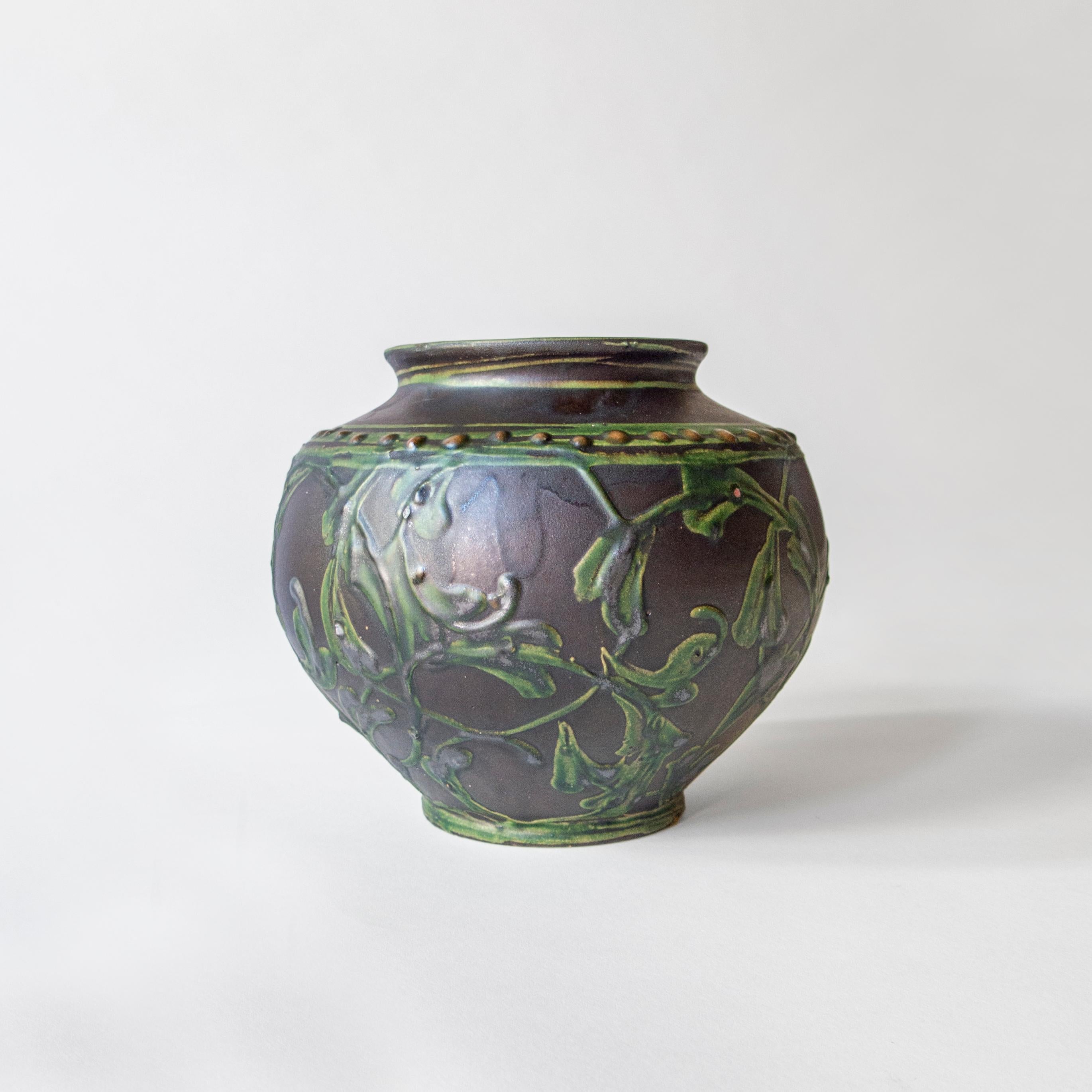 Each hand decorated with foliate pattern in bas relief, glazed in various shades of blue, green, and dark gray with umber accents. Each signed underneath: HAK

Vase: Height 7.75