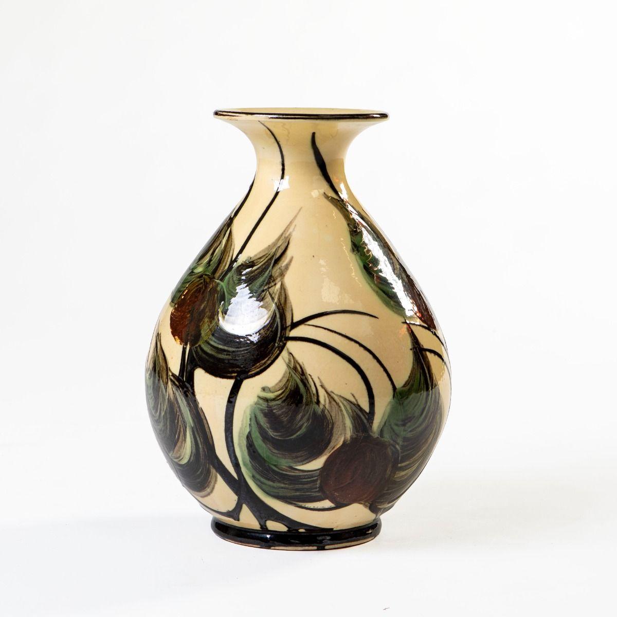 Ce magnifique vase en céramique a été conçu par Sven Hammershøi et produit par Kähler au Danemark vers 1930.
Réalisé en grès émaillé, il présente une base beige douce, richement décorée de motifs de feuilles peints à la main dans des tons vert foncé