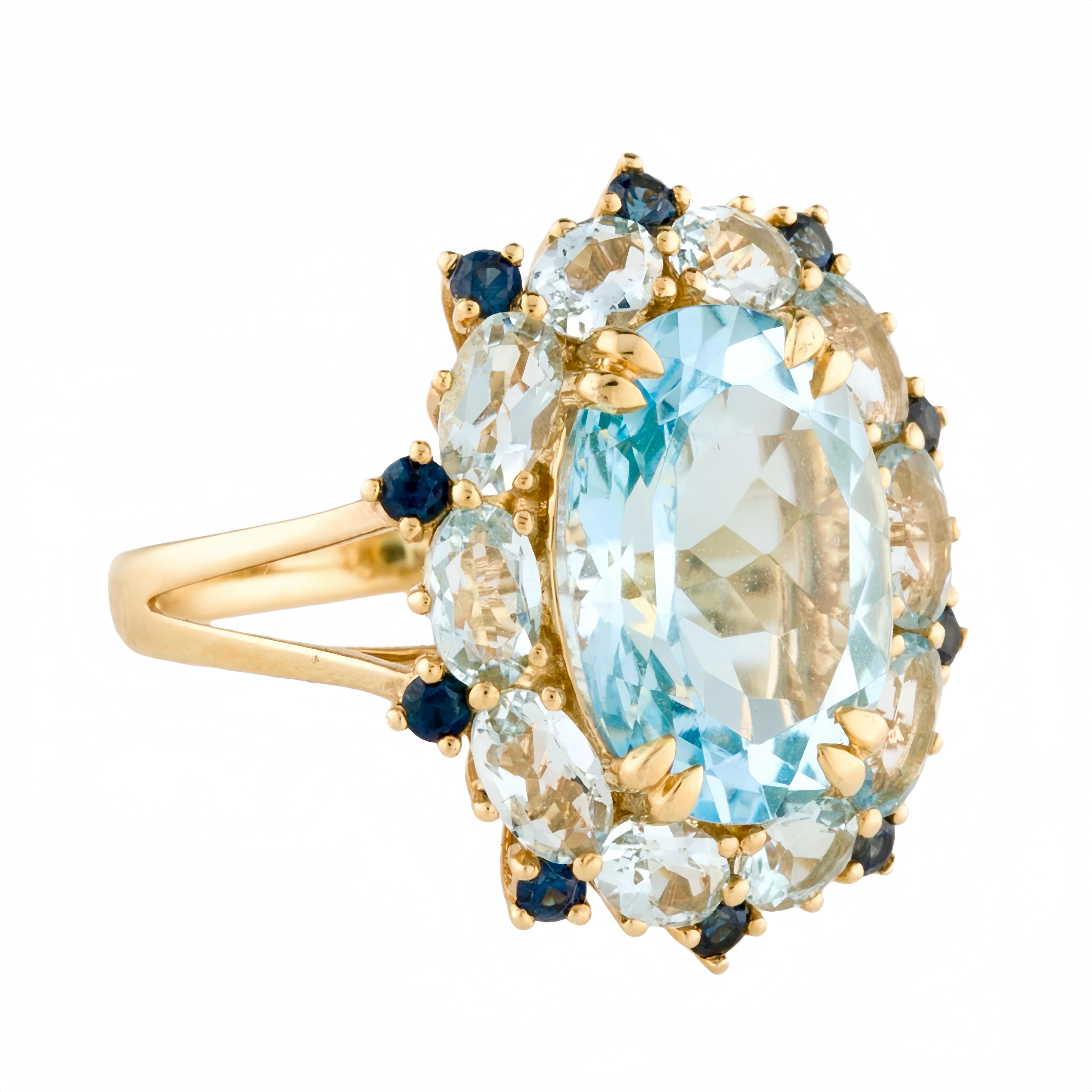 Discover Kai Blue Topaz Aquamarine Sapphire Cluster Cocktail Ring in 14k yellow gold, a true masterpiece of elegance and sophistication. This exquisite piece of jewelry showcases a stunning 7.20-carat topaz at its center, radiating a mesmerizing
