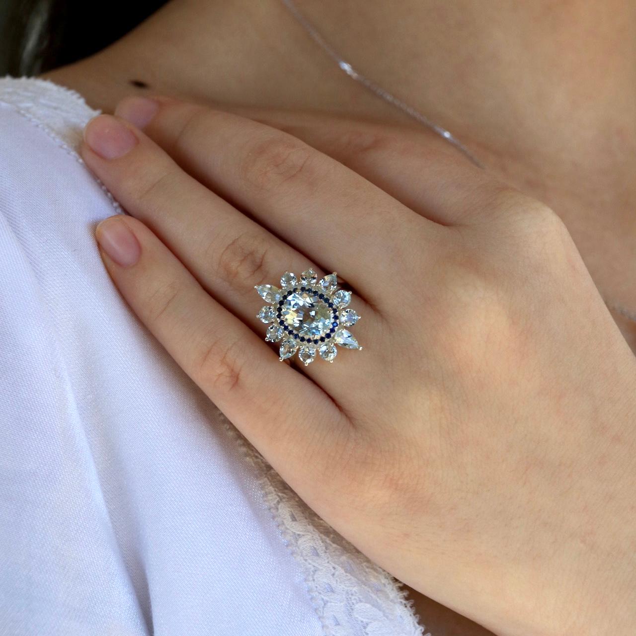 Step into timeless elegance with this Vintage Style Natural Aquamarine and Sapphire Cocktail Ring. At its heart lies a breathtaking oval-cut aquamarine gemstone, radiating the serene hues of clear blue skies and tranquil waters. Encircling the