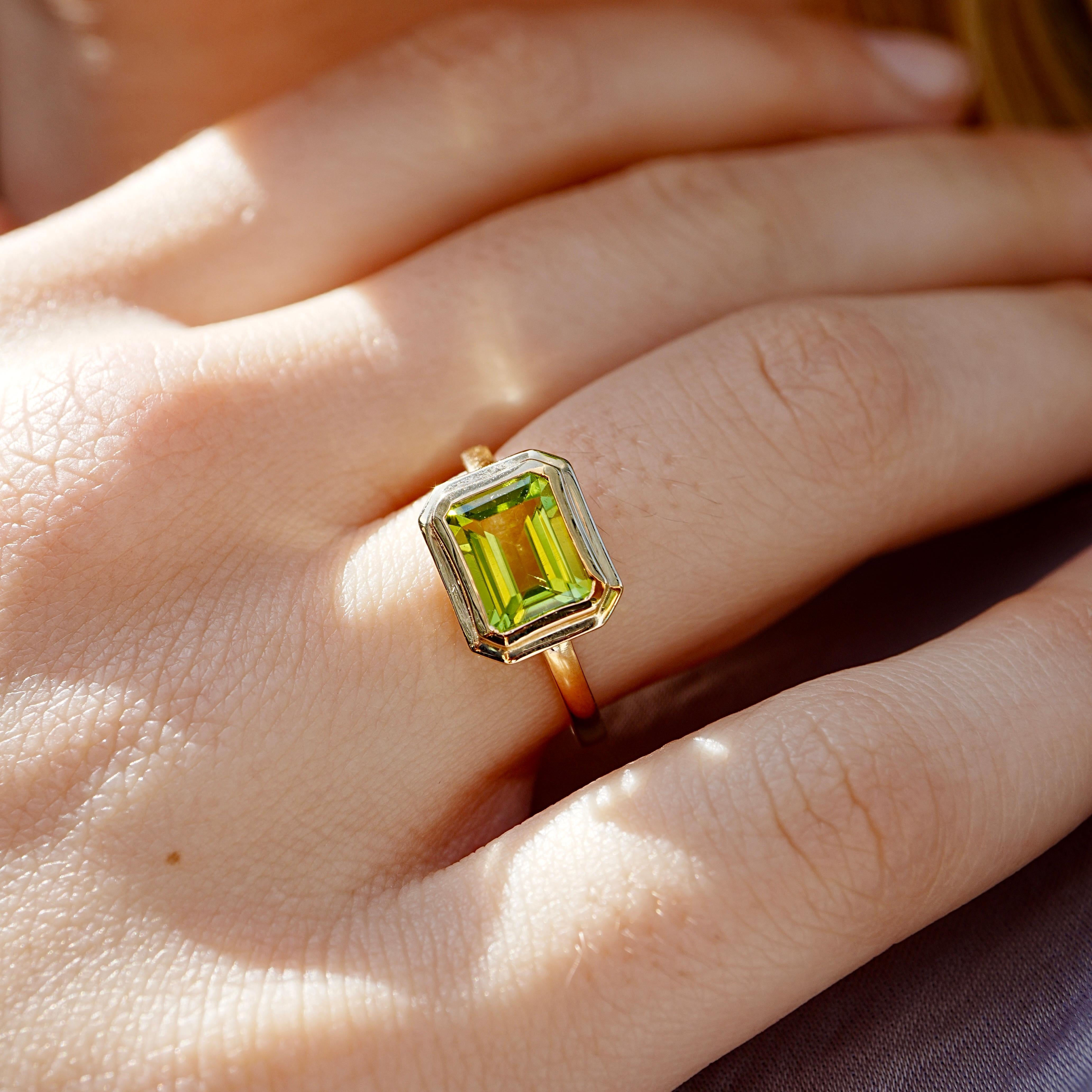 Avec ses lignes architecturales épurées et sa teinte rafraîchissante, cette bague East-West offre une touche moderne à l'élégance classique. Le péridot taille émeraude de 2,80ctw est serti horizontalement dans de l'or jaune 14K, soulignant l'éclat