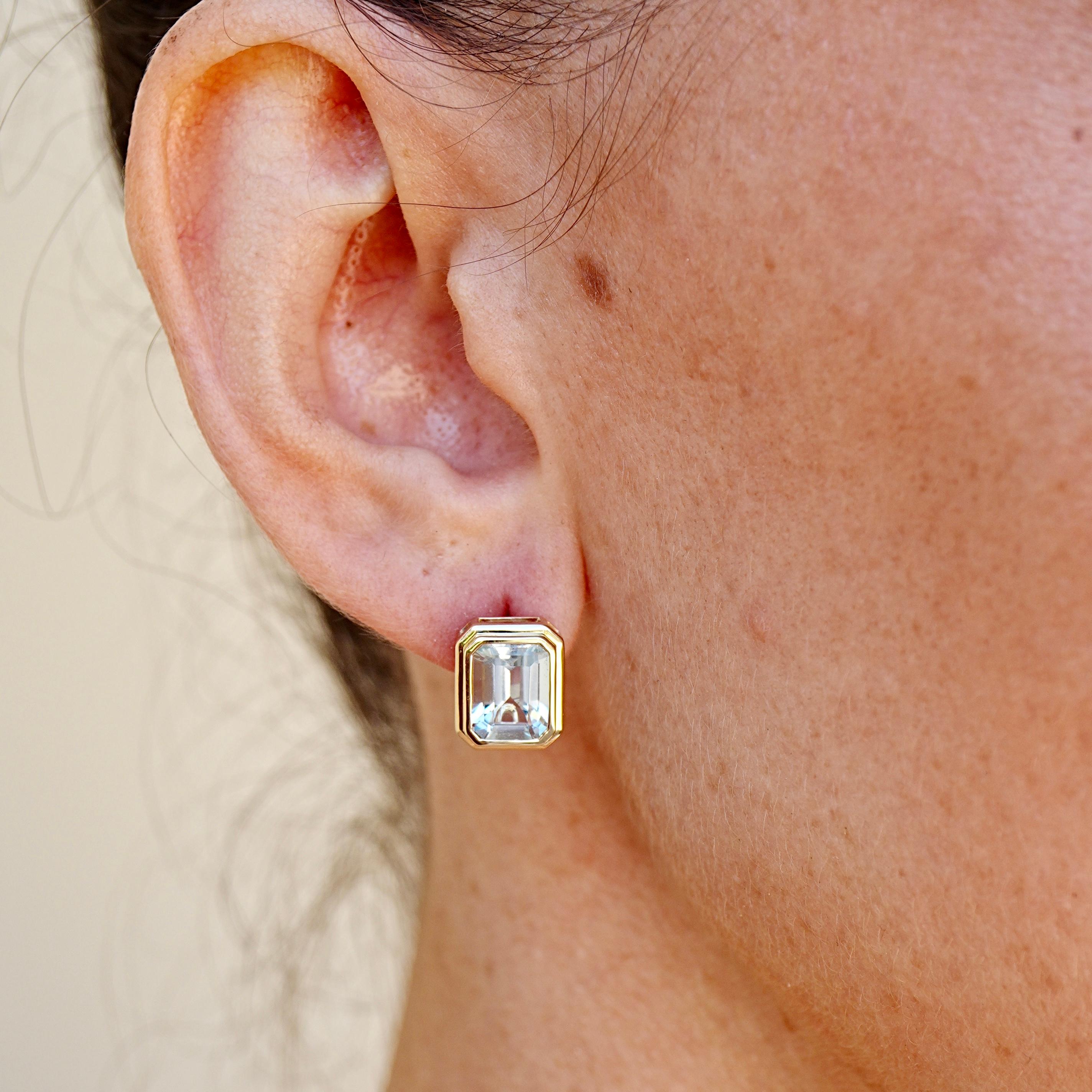 Diese eleganten Bella-Ohrringe sind mit einem Paar Aquamarine im Smaragdschliff besetzt, die zusammen 4,40 Karat ergeben. Ihre eisblaue Klarheit wird durch saubere 14-karätige Gelbgoldfassungen hervorgehoben, die Symmetrie und Licht betonen.

Dieses