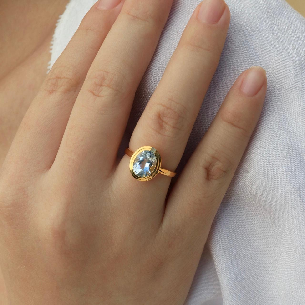 Enhance your elegance with the Kai Bella Oval Natural Aquamarine Ring, a captivating piece that embodies the serene beauty of sky-blue aquamarine. Crafted in luxurious yellow gold, this ring features an exquisite, eye-clean oval aquamarine gemstone