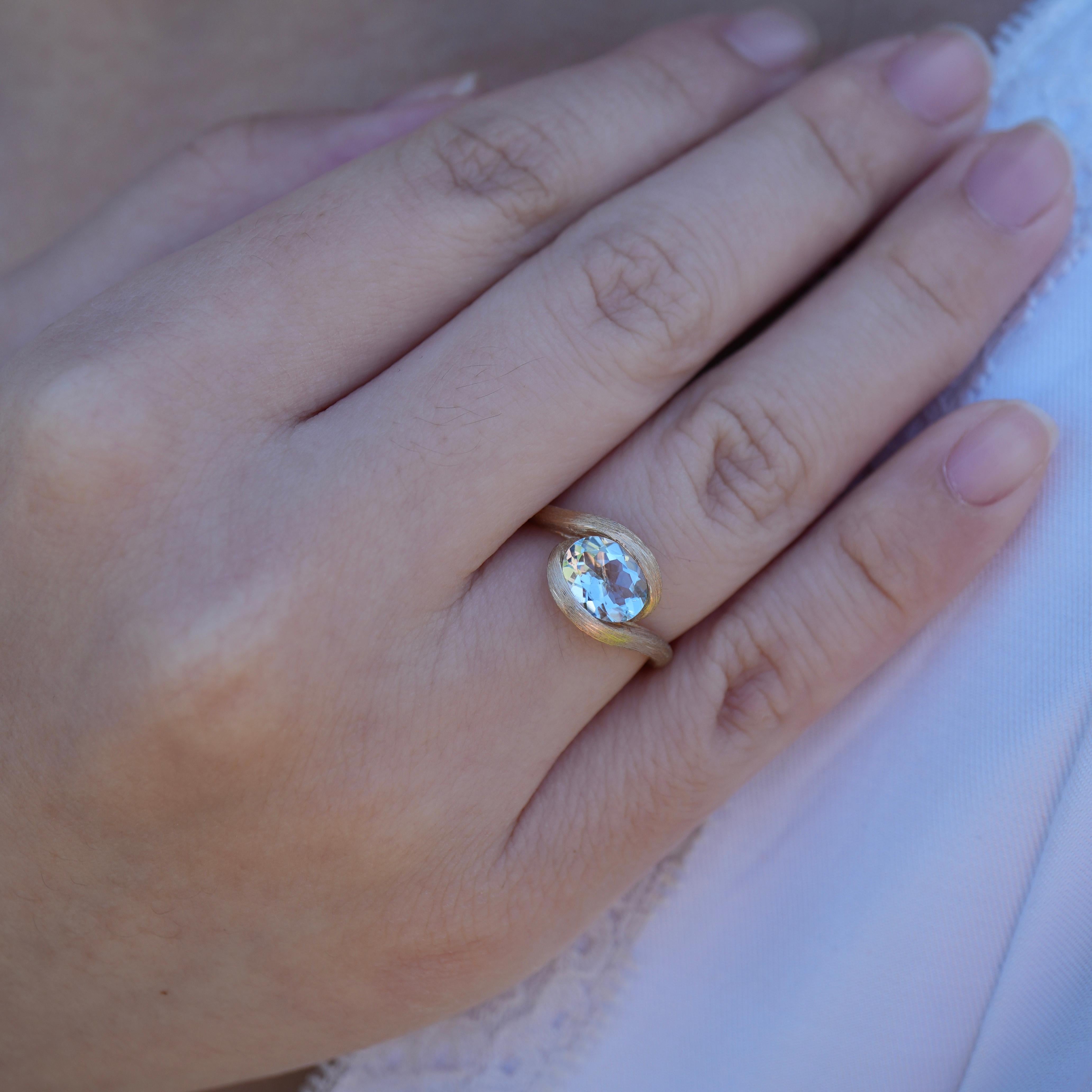 Une ode au mouvement et à l'immobilité en parfait équilibre. La bague Eternal Wave de Kai présente une aigue-marine ovale lumineuse sertie horizontalement dans un anneau sculptural en or 14 carats brossé. L'arc fluide embrasse la pierre précieuse