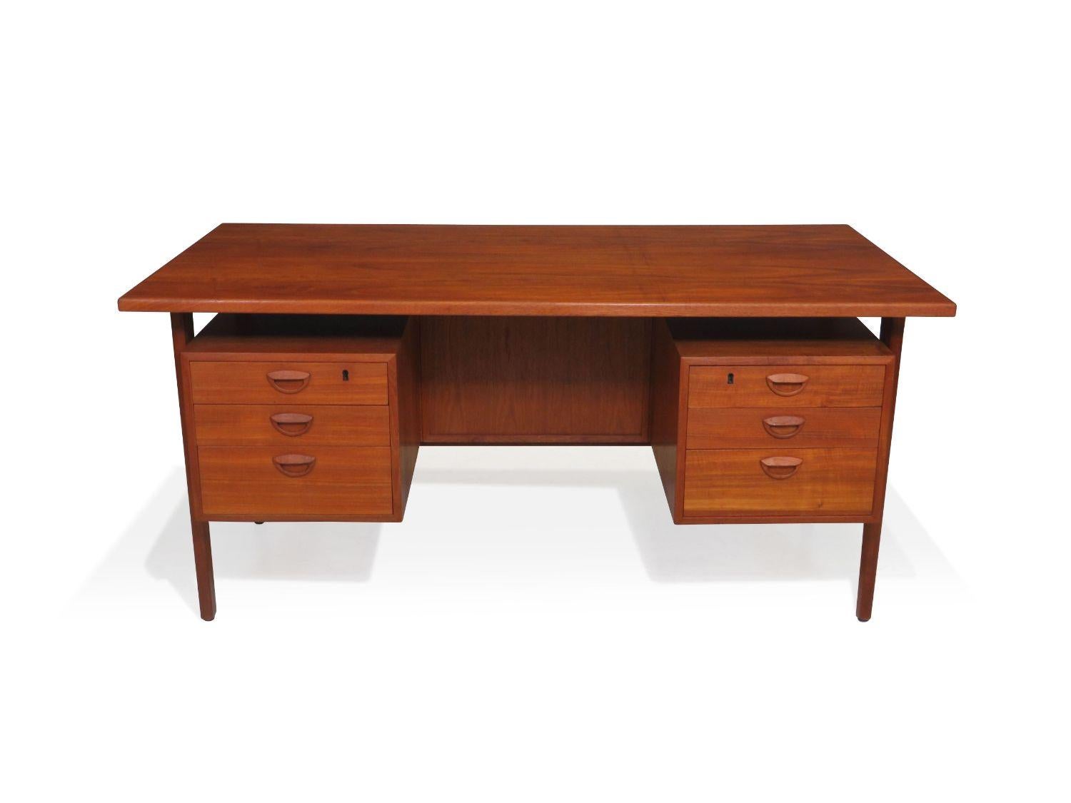 Danish Teak desk designed by renown Danish designer Kai Kristiansen for Feldballes Mobelfabrik, Model FM 60, circa 1958 Denmark. The desk is handcrafted of old growth teak and features two banks of drawers with sculpted pulls. Finely restored in