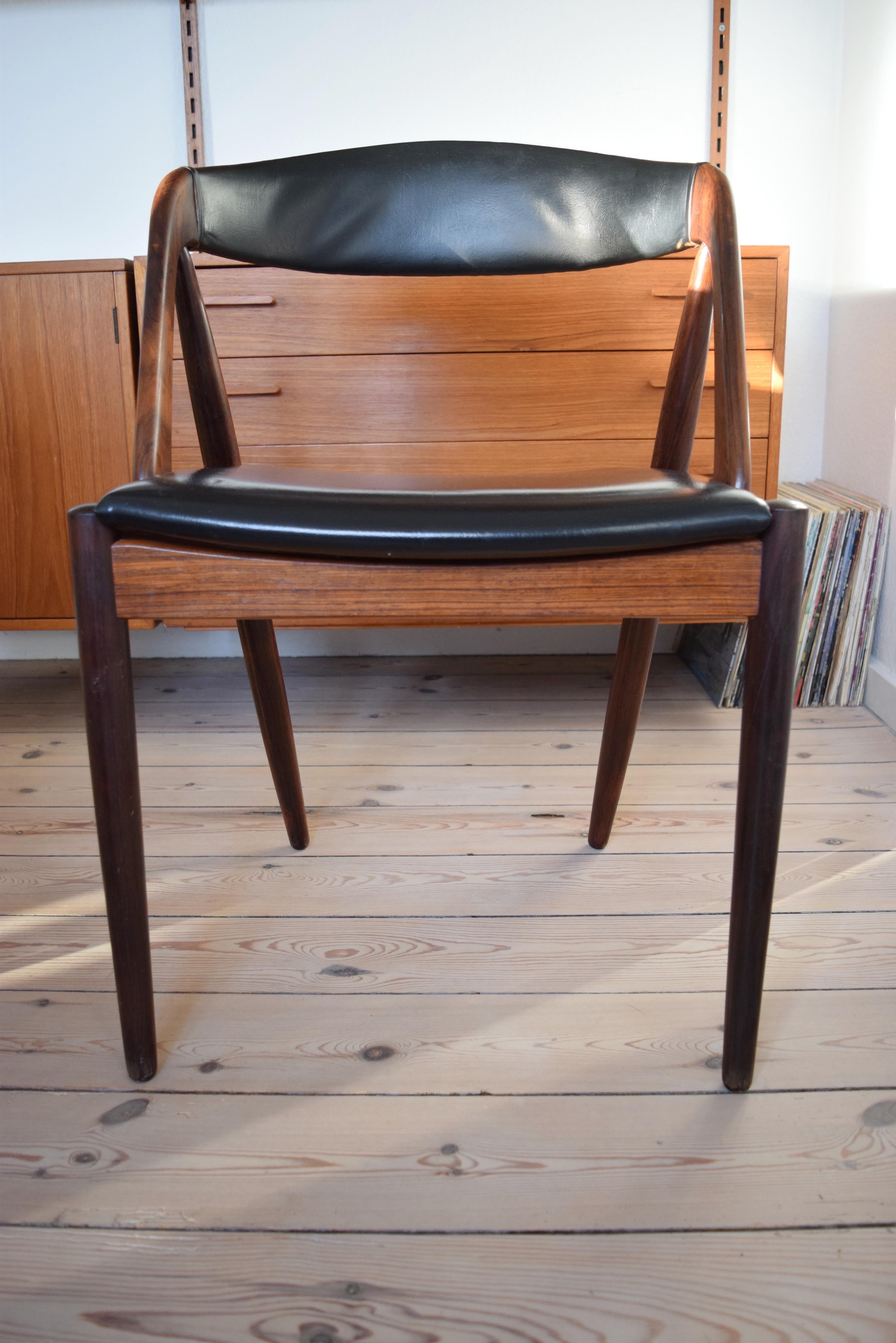 Dining chair by Kai Kristiansen for Schou Møbelfabrik, Denmark. The frame is made of rosewood and the seat and backrest is covered in the original black skai. This model features a deep curved backrest for extra comfort.