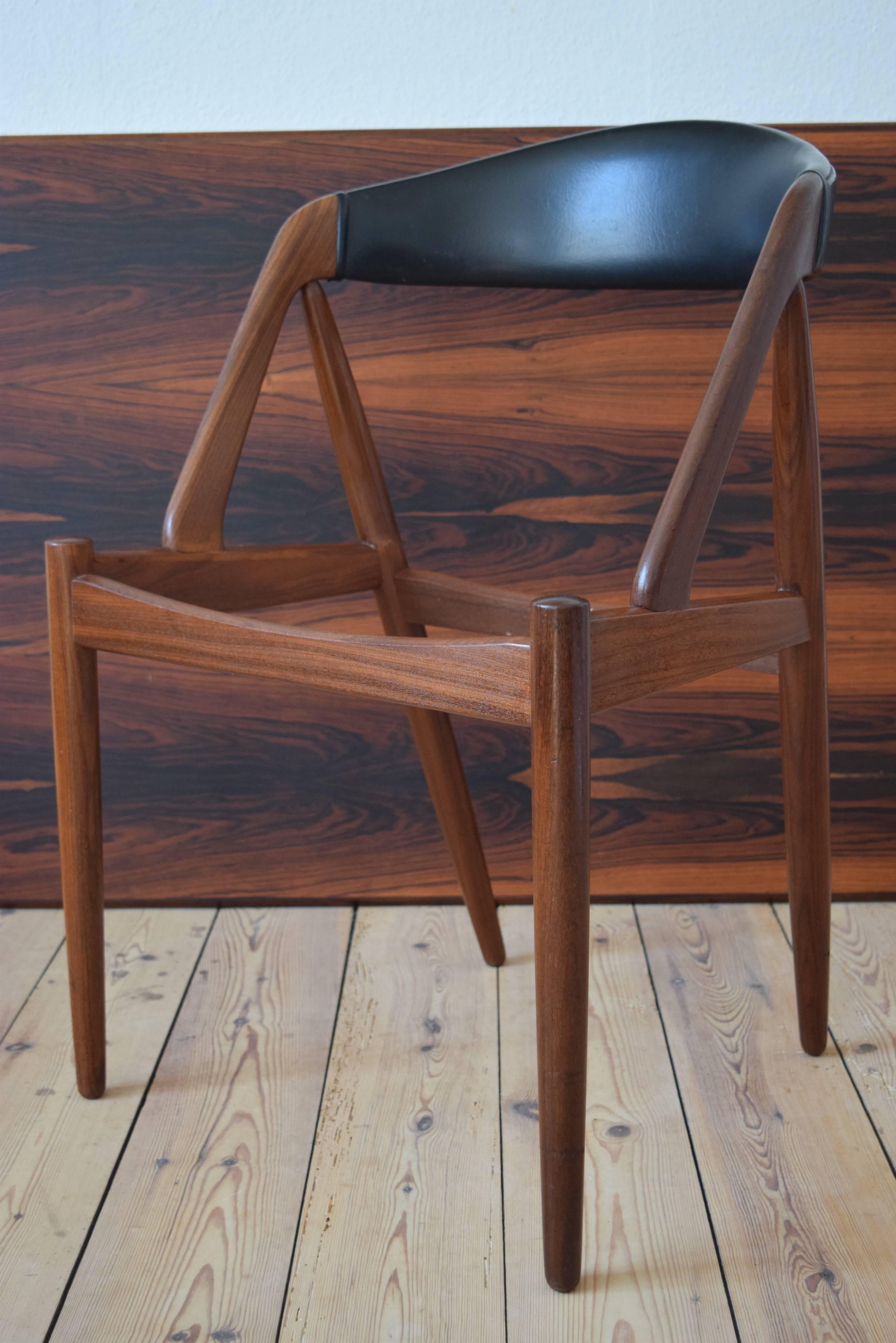Set of three dining #31 chairs by Kai Kristiansen for Schou Møbelfabrik, Denmark. The frame is made of teak and the seats and backrests are covered in the original black skai. This model features a deep curved backrest for extra comfort. We can