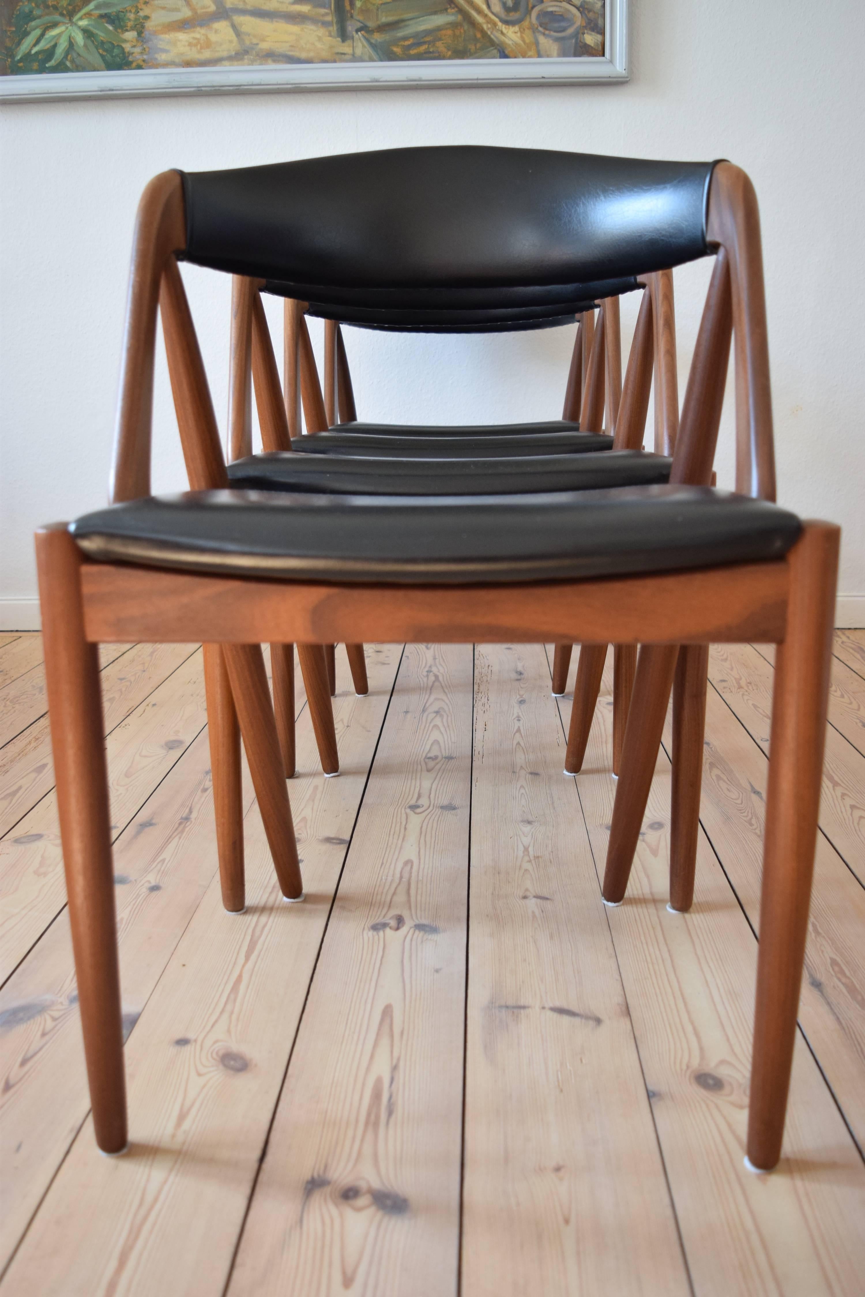 Set of four dining #31 chairs by Kai Kristiansen for Schou Møbelfabrik, Denmark. The frame is made of teak and the seats and backrests are covered in the original black skai. This model features a deep curved backrest for extra comfort. We can these