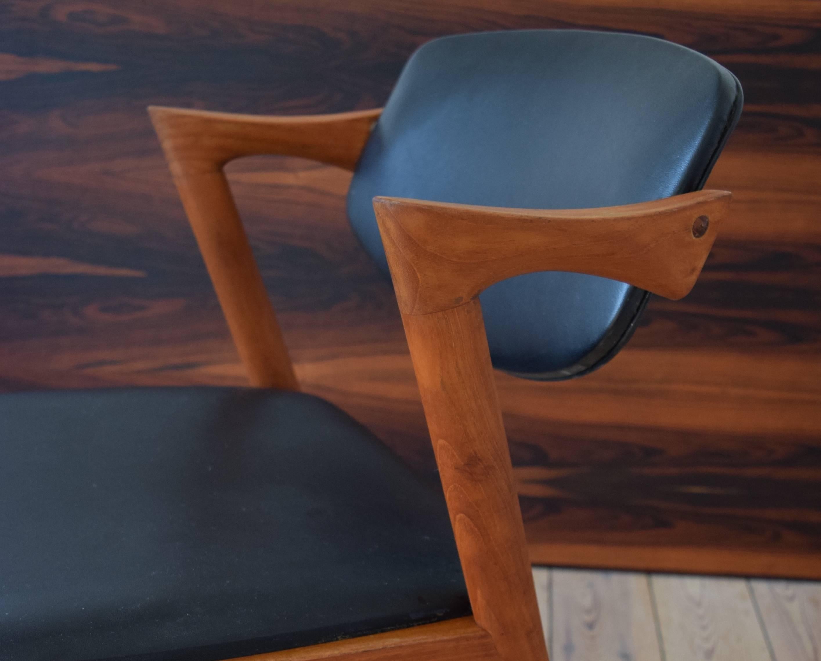 Kai Kristiansen model 42 teak dining chair, manufactured by Schou Andersen in the 1960s. This chair is covered in black skai. Chair frame has been re-finished, cleaned and oiled. Some small marks here and there commensurate with age, but overall