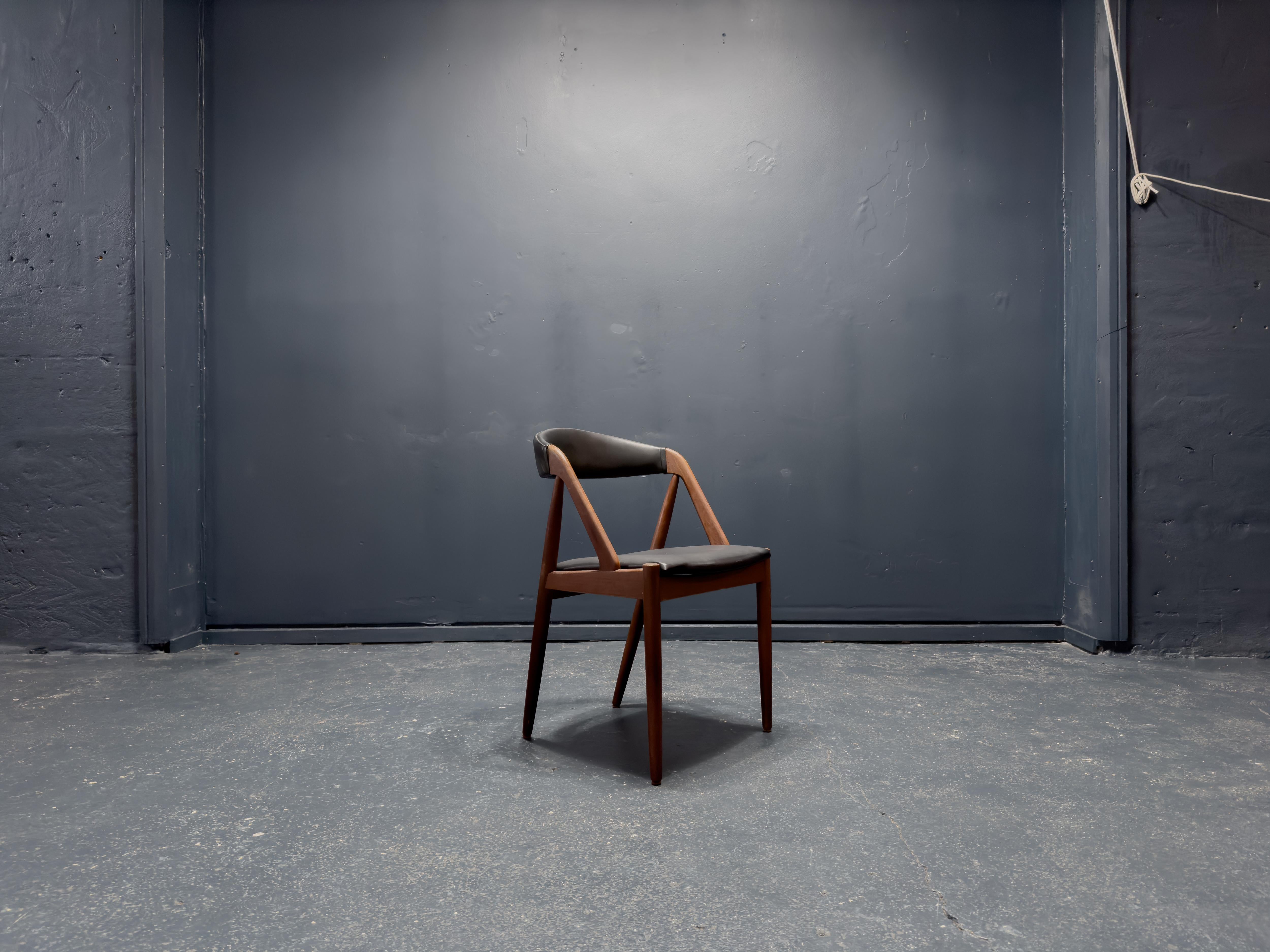 This Kai Kristiansen Model 31 chair, designed in the 1960s and manufactured by Schou Andersen Møbelfabrik, seamlessly blends elegance, comfort, and craftsmanship. Constructed from rich, sculpted teak, the frame features fluid, organic lines that
