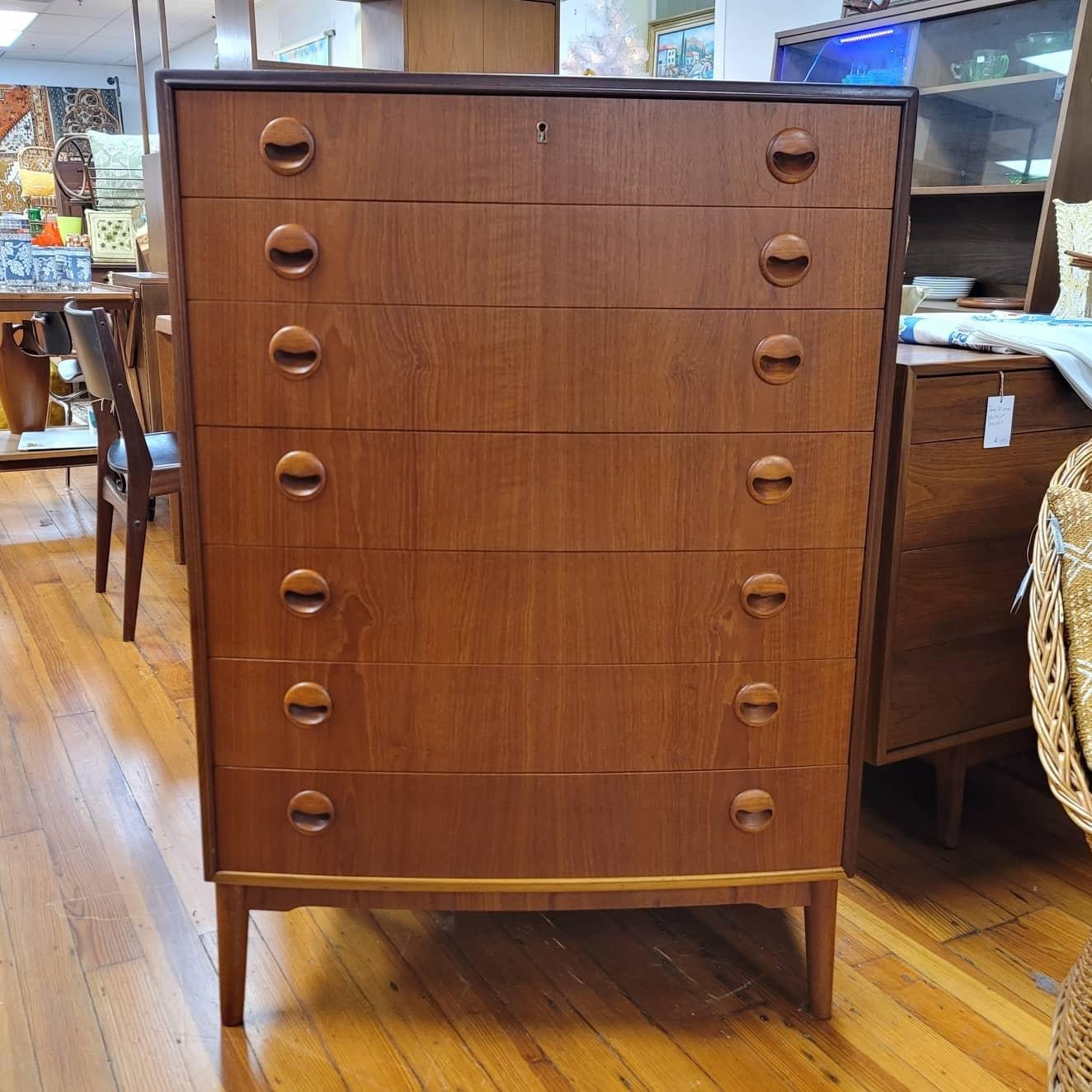 This seven drawer teak tall chested was designed by Kai Kristiansen with its distinct eyelash pulls and curved front. This piece was recently imported from Denmark and has been professionally restored and is in excellent condition. Perfectly sized