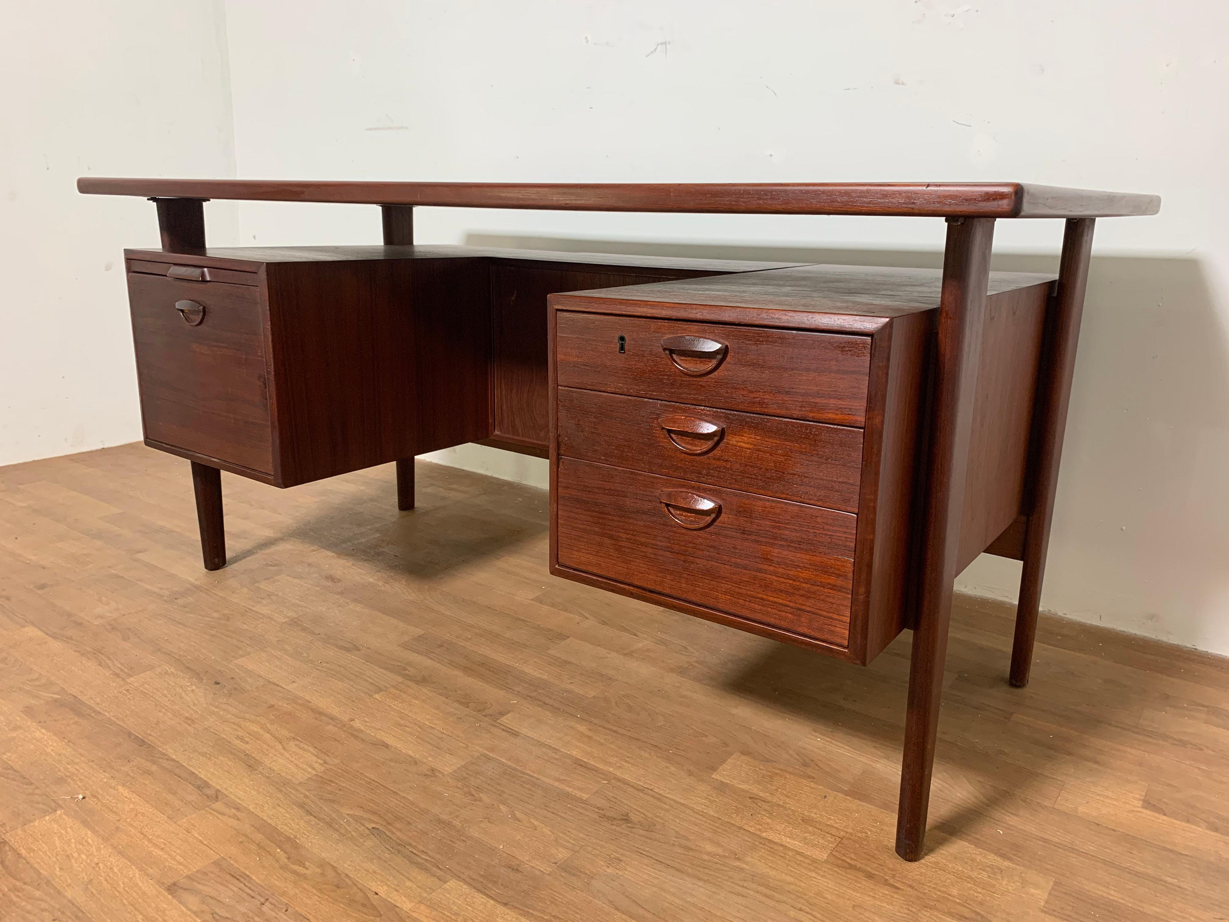 Teak desk by Kai Kristiansen, designed in 1958 for Feldballes Mobelfabrik, Denmark. Three drawers on the right and file cabinet drawer on the left, all featuring Kristiansen's signature carved handles. Above the file cabinet drawer is a pull out