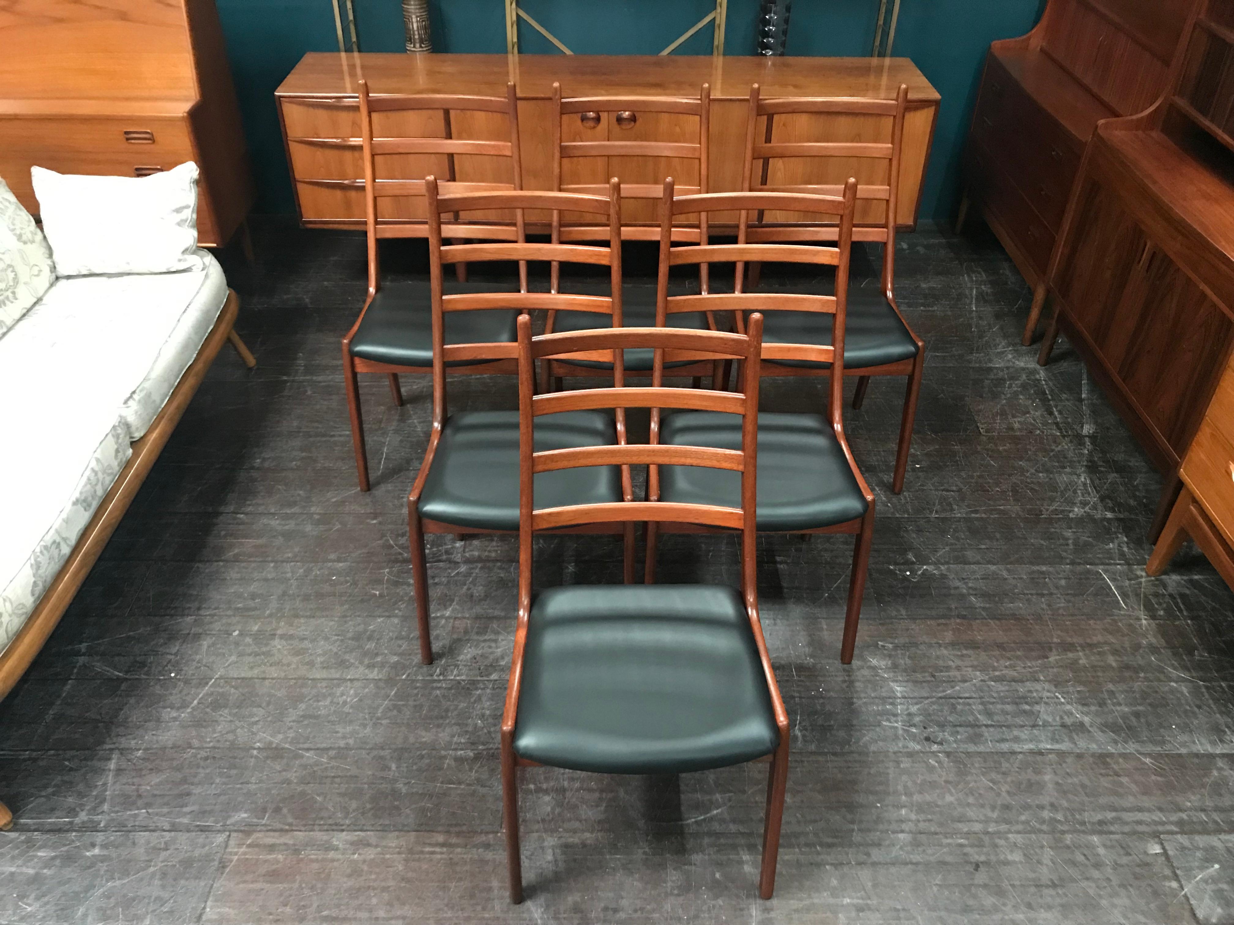 This is a set of very desirable midcentury dining chairs with black vinyl seat pads designed in Denmark in the 1960s by Kai Kristiansen and manufactured by Korup Stolefabrik. These beautiful high back chairs have a traditional 4 bar ladderback