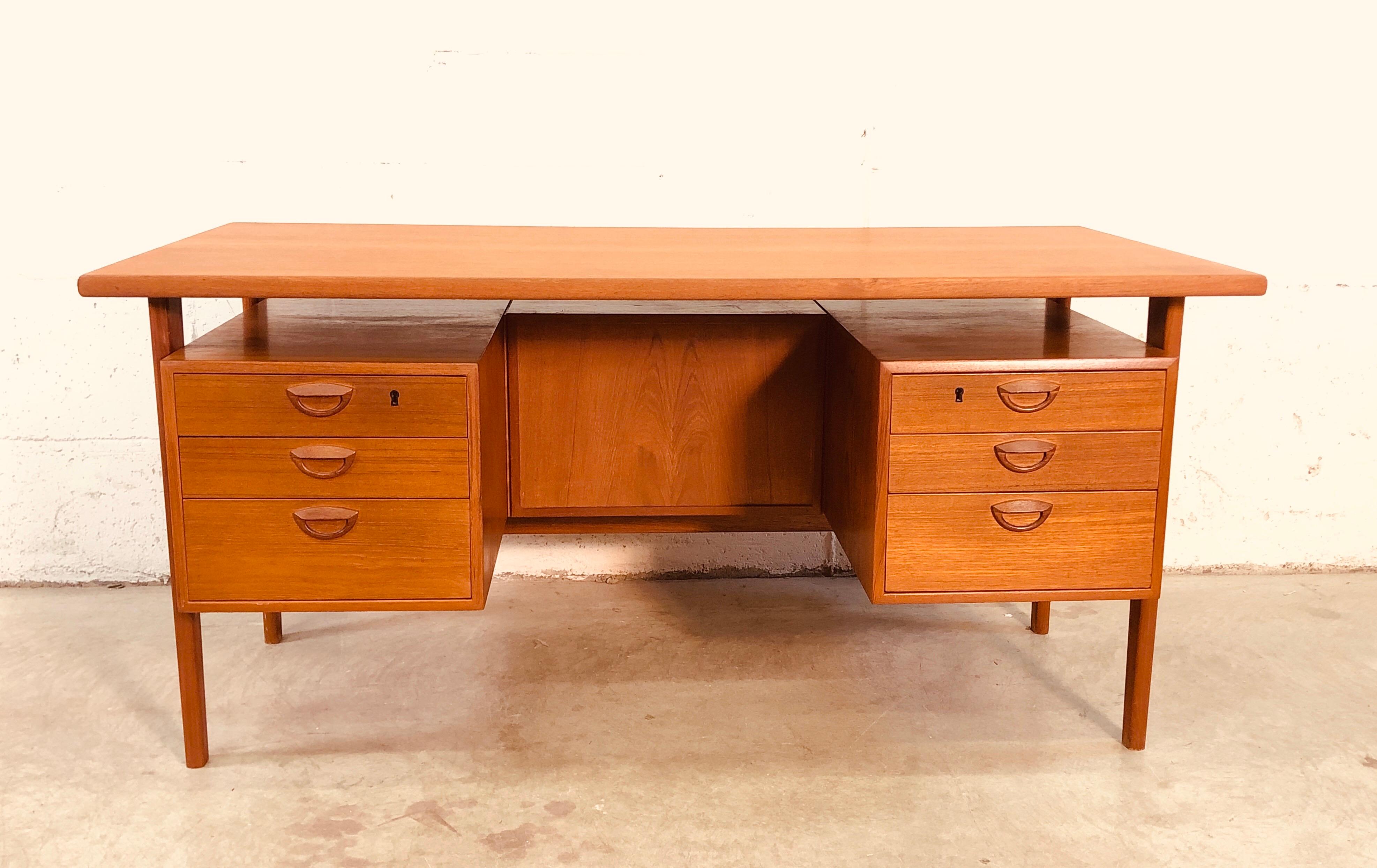 Executive Danish teak desk designed by Kai Kristiansen with a floating top and six drawers for storage. The desk also has built in storage for books or display. In excellent refinished condition. No marks. Knee hole measures: 20.75” L x 17.5” D and