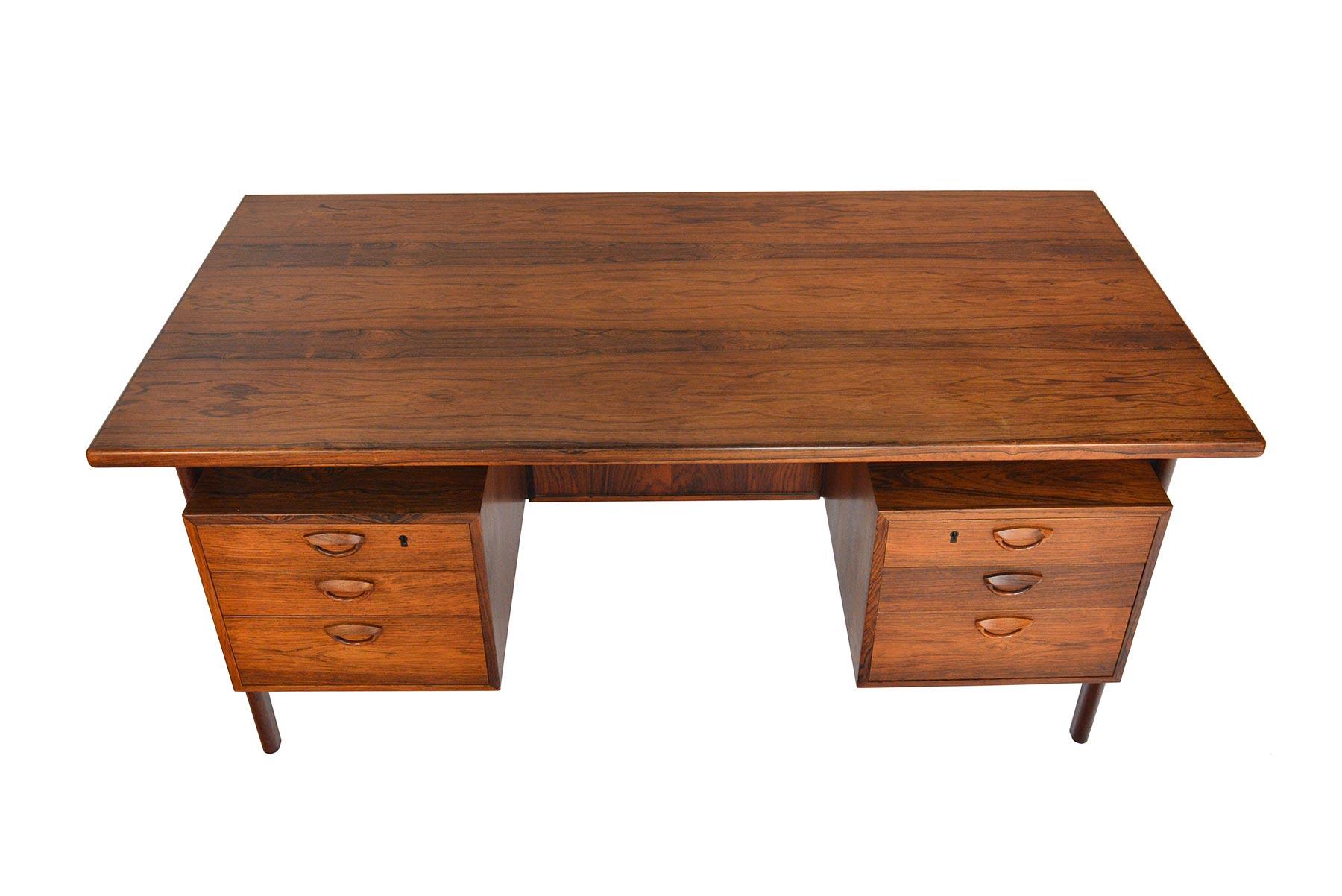 This Danish modern executive desk Model FM 60 in Brazilian rosewood was designed by Kai Kristiansen for Feldballes Møbelfabrik in 1957. The large work surface is supported by four sculpted legs which key into place. The kneehole is nestled between