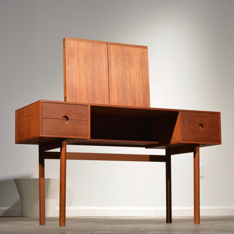 Designed by Kai Kristiansen for Aksel Kjersgaard in the mid-1960s, model 40. Solid teak drawer fronts with striking round recessed pulls. The mirror angle adjusts by sliding the teak cubes up and down the mounting posts.
Great condition with age