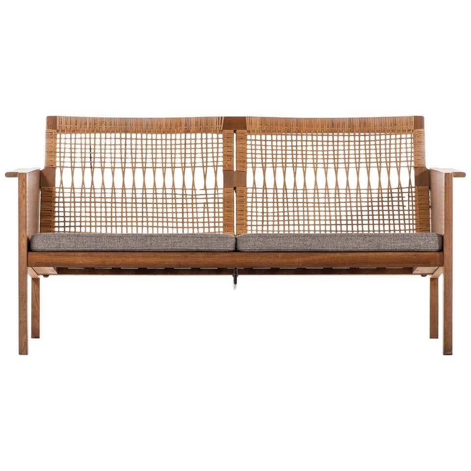 Rare 2-seater sofa designed by Kai Kristiansen and produced by Christian Jensen Møbelsnedkeri in Denmark in the 1960’s. This sofa features a wooden frame with woven rattan backrests. Recently reupholstered in grey wool fabric. In very good condition