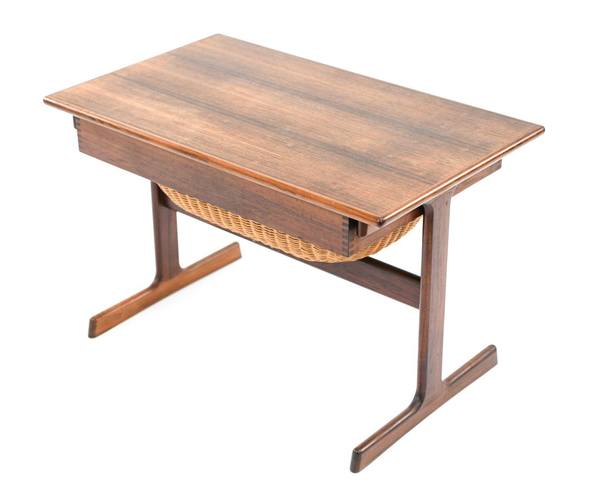 This Danish midcentury rosewood sewing table was designed by Kai Kristiansen for Vildbjerg Mobelfabrik, circa 1960s. Featuring a single compartmentalized drawer and inset basket for optimal, organized storage.