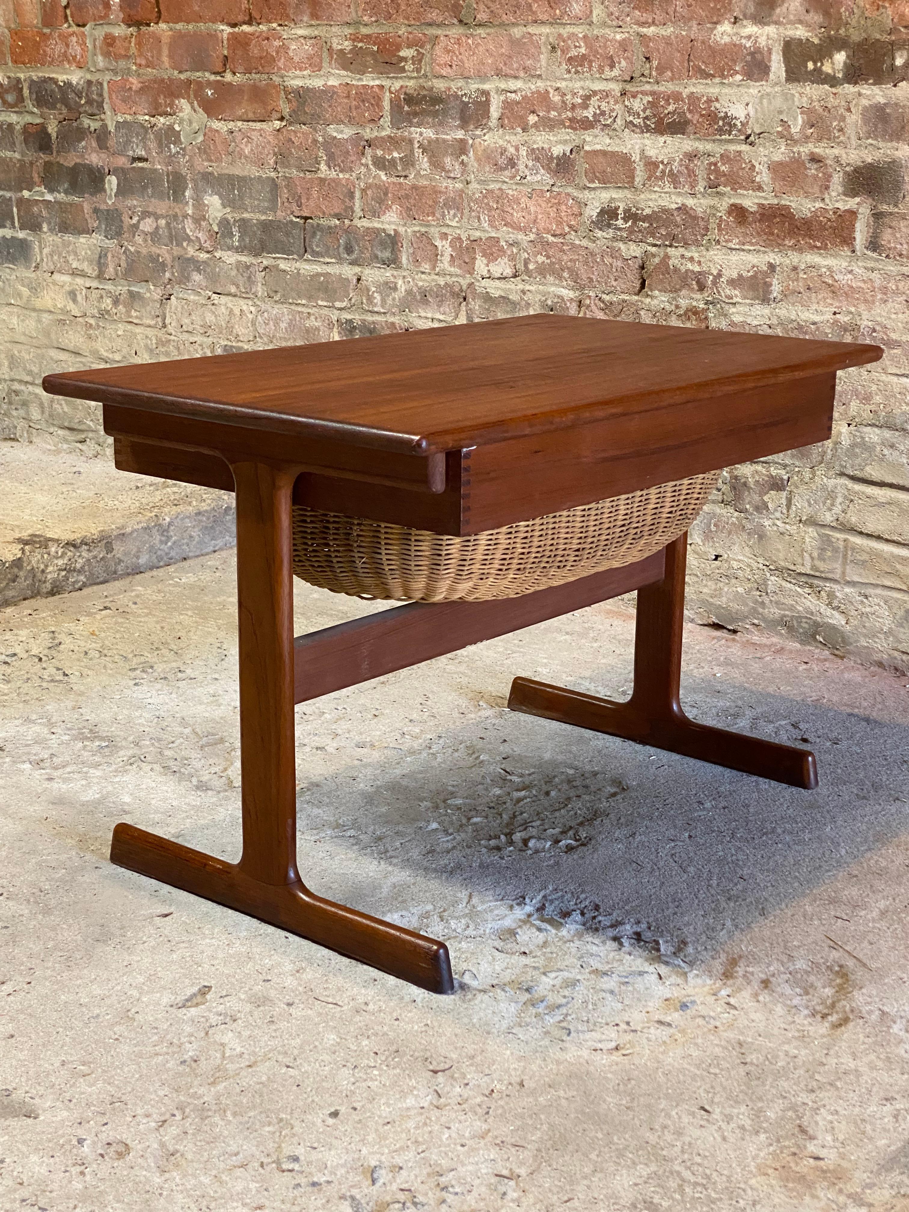Stylish Danish Modern teak and wicker sewing stand designed by Kai Kristiansen for Vildbjerg Mobelfabrik, Denmark. Circa 1960. Featuring a roomy slide out wicker basket and a divided utility drawer for tools of the trade like thread spools, knitting