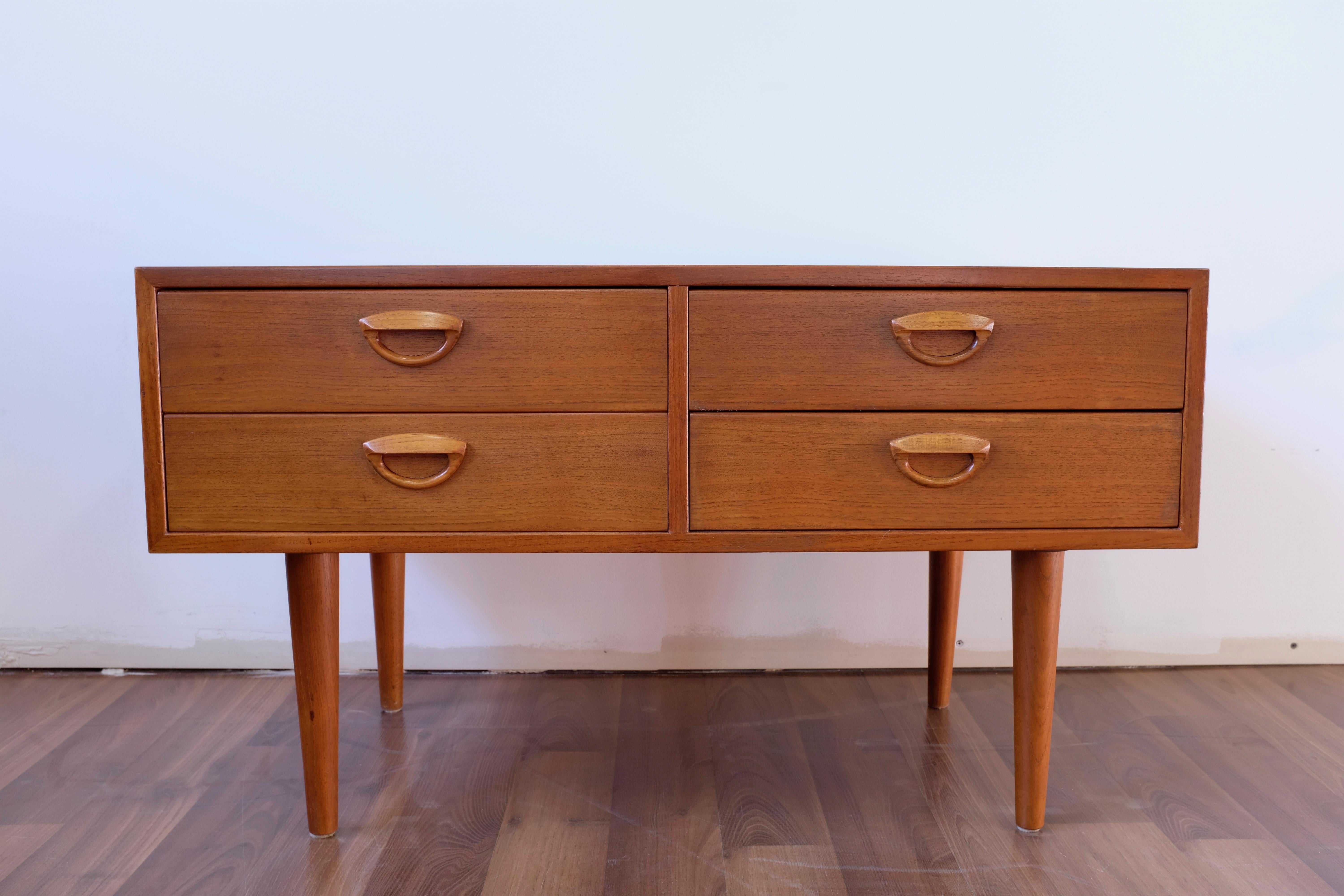 A low chest of drawers in teak designed by Kai Kristiansen, suitable as a dresser, nightstand or TV stand. Manufactured in Denmark by Feldballes Møbelfabrik.

The four solid wood drawers are constructed using dovetails and have elegant solid teak
