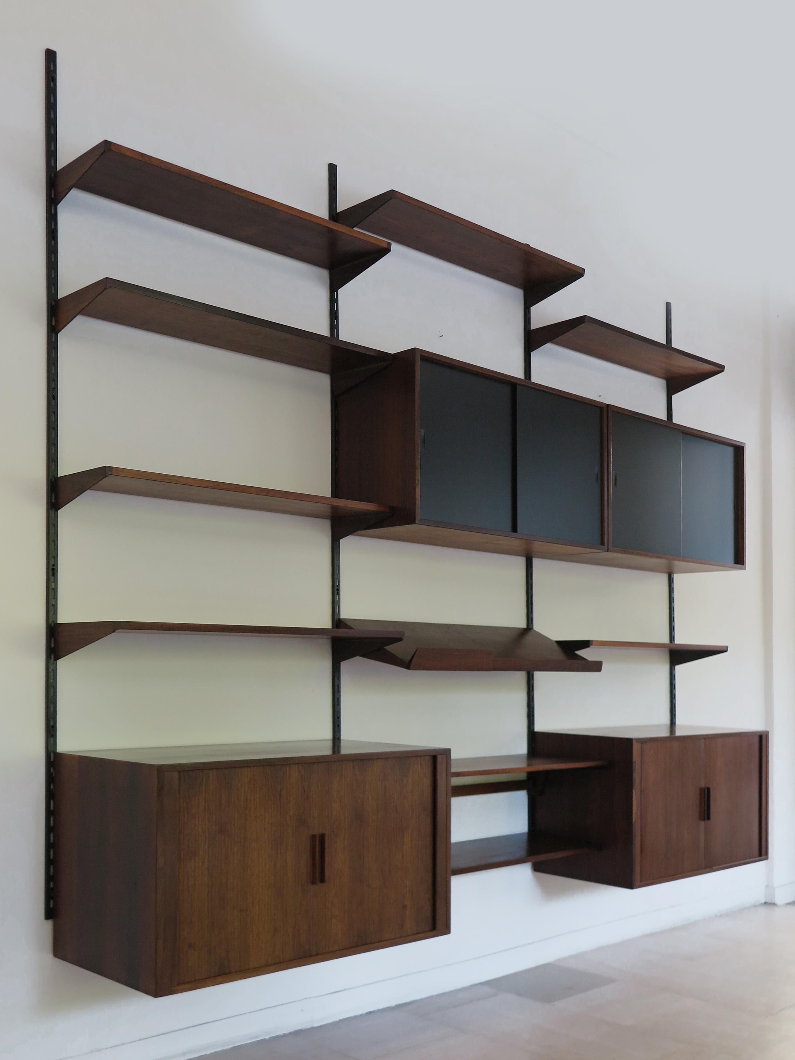 Scandinavian mid-century moder design dark wood wall system designed by Kai Kristiansen and produced by FM Mobler, consisting of 9 shelves of different depths,  1 lectern shelf, 2 containers with roller shutter doors and 2 containers with black